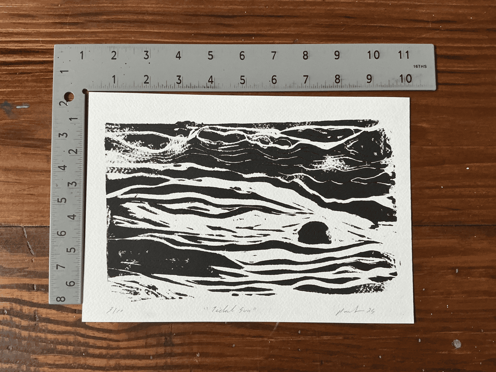 Limited black ink relief print of an abstract "tidal sun" with square ruler to show size.