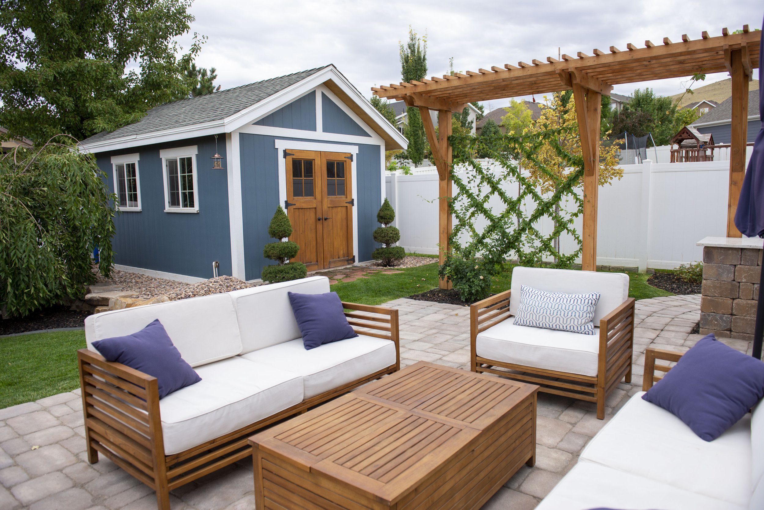 Backyard landscaping by Kodiak Landscape® in Cottonwood Heights, UT, including a custom shed, arbor and paver patio with sitting and entertainment area.