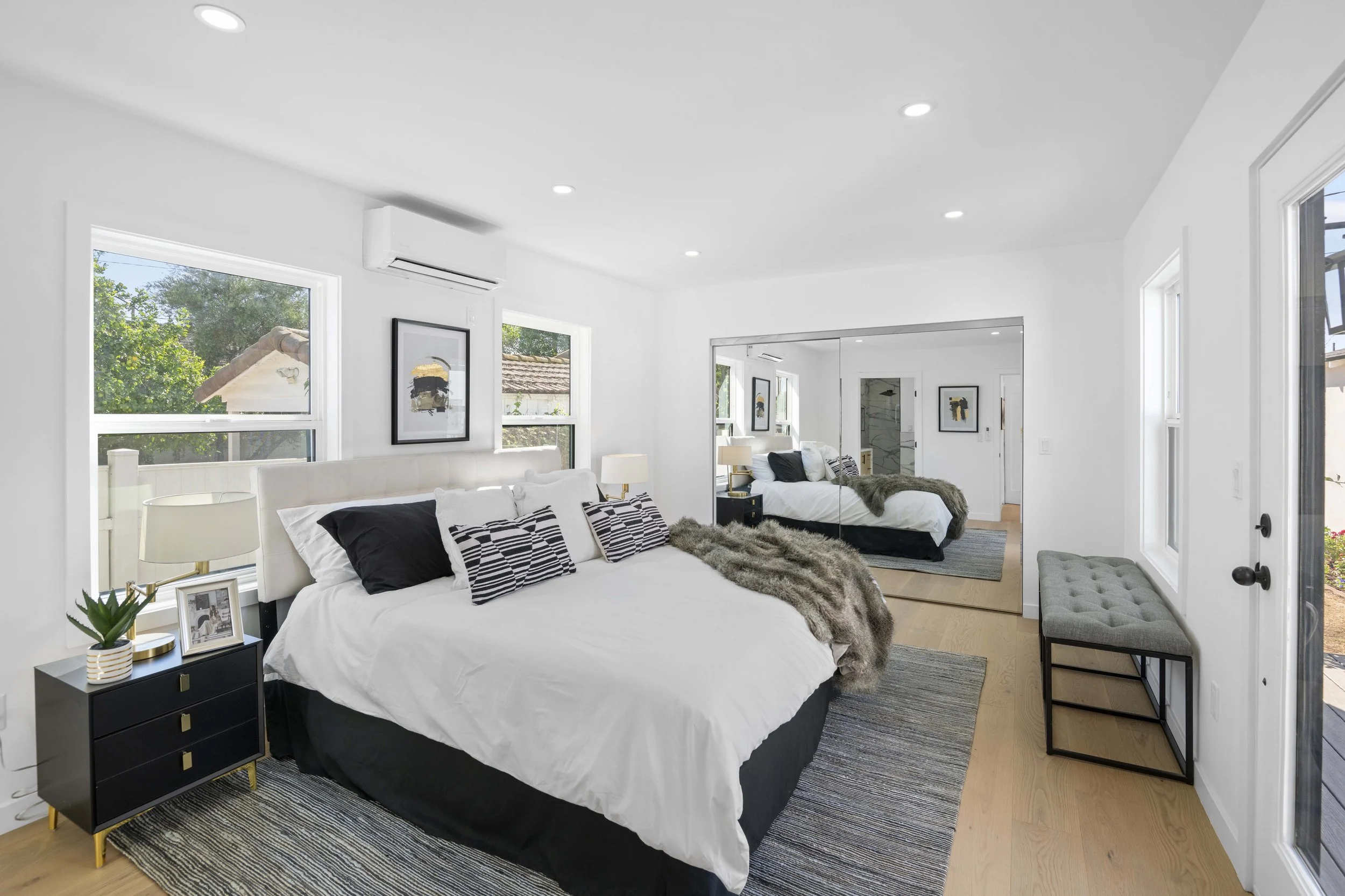 Modern LA bedroom with black and white bedding, mirrored closet doors, and gold-accent nightstand — professionally captured by Intuition Real Estate Media.