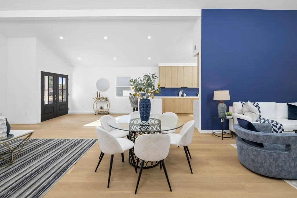 Affordable real estate photography of an open-concept LA home – dining and living room with designer staging and blue accent wall, shot by Intuition Real Estate Photography & Imaging.