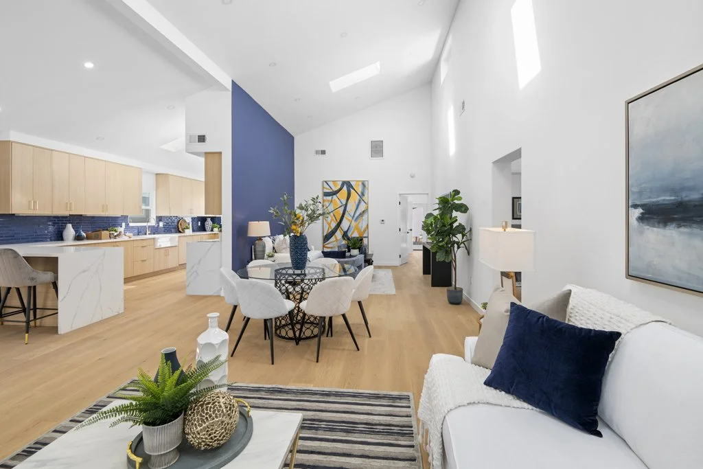 Modern open-concept living and dining room with white sofa and kitchen staging – affordable Los Angeles real estate photography by Intuition Real Estate Photography & Imaging.
