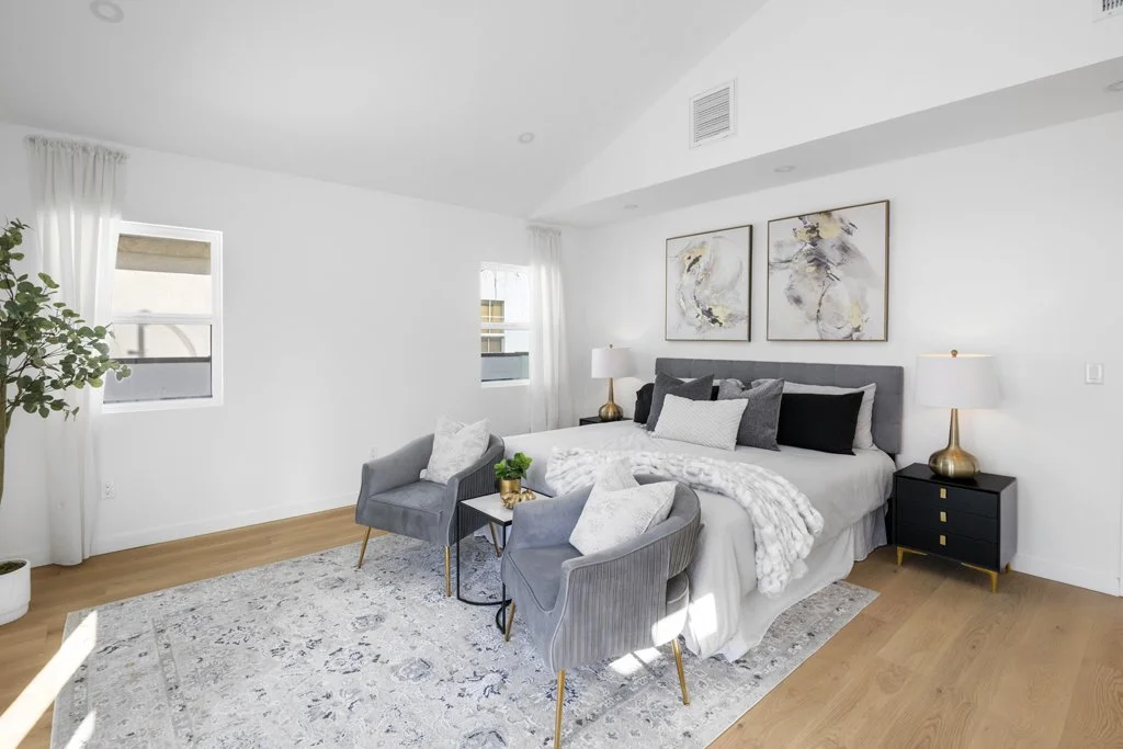 Affordable interior real estate photo of LA bedroom with gray upholstered bed, abstract art, and light hardwood floors by Intuition Real Estate Photography & Imaging.