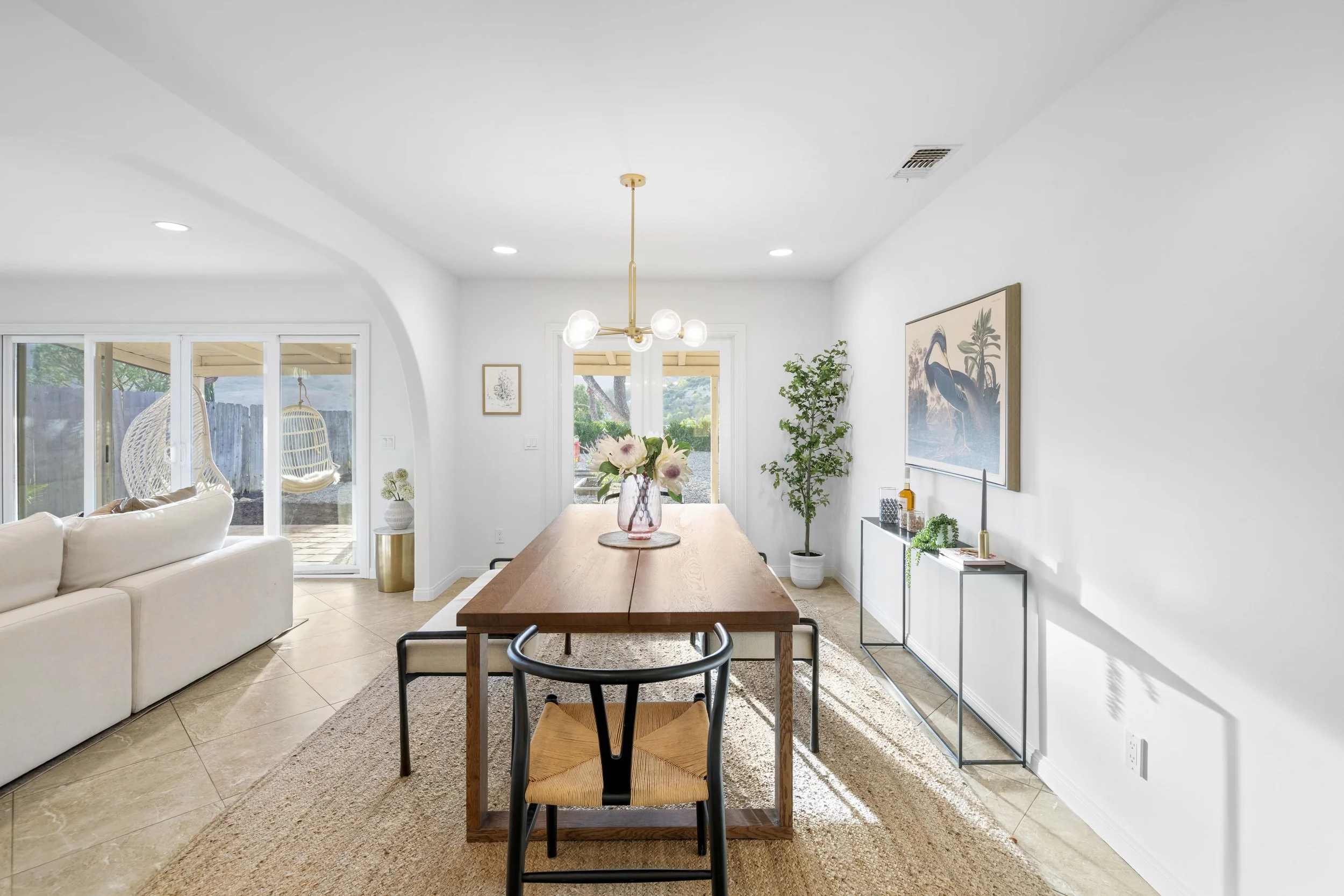Elegant dining room with flowers and sliding doors to hanging patio chairs — staged and photographed by Intuition Real Estate Media for LA property marketing.