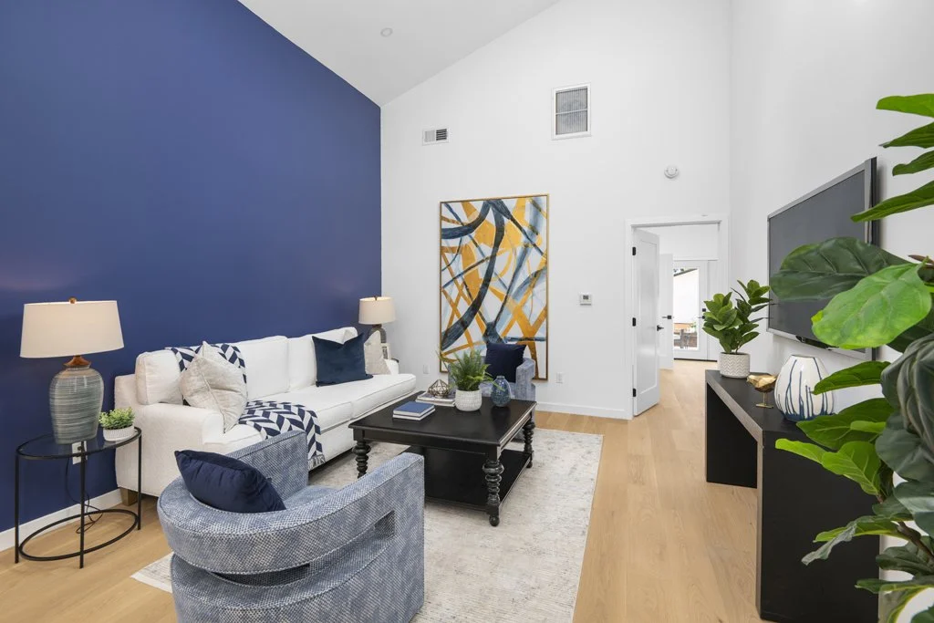 Best interior real estate photo of LA living room with blue accent wall, white sofa, abstract art, and fireplace – captured by Intuition Real Estate Media.