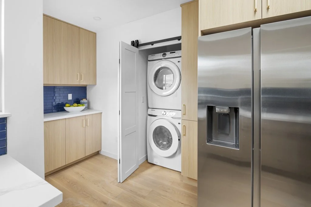 Interior photo of laundry room in staged Los Angeles home – stacked washer/dryer, wood cabinets, and modern layout by Intuition Real Estate Media.