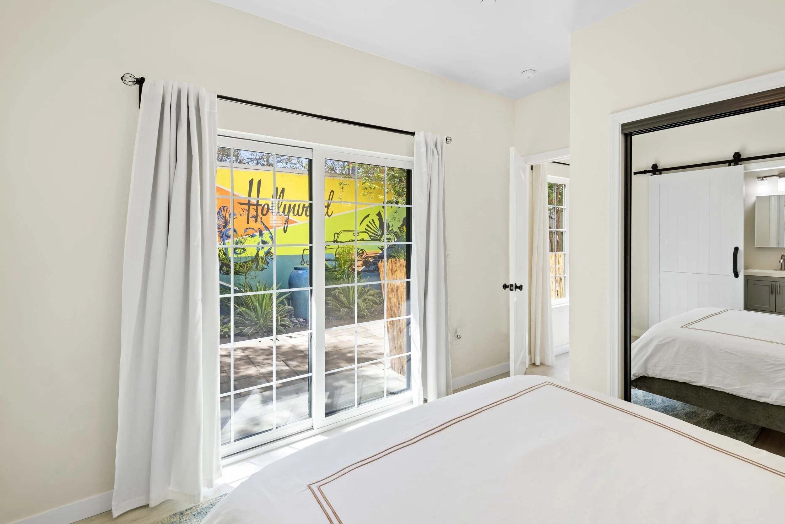 Serene Los Angeles bedroom with sliding barn door and patio access — captured by Intuition Real Estate Media to highlight indoor-outdoor flow for modern listings.
