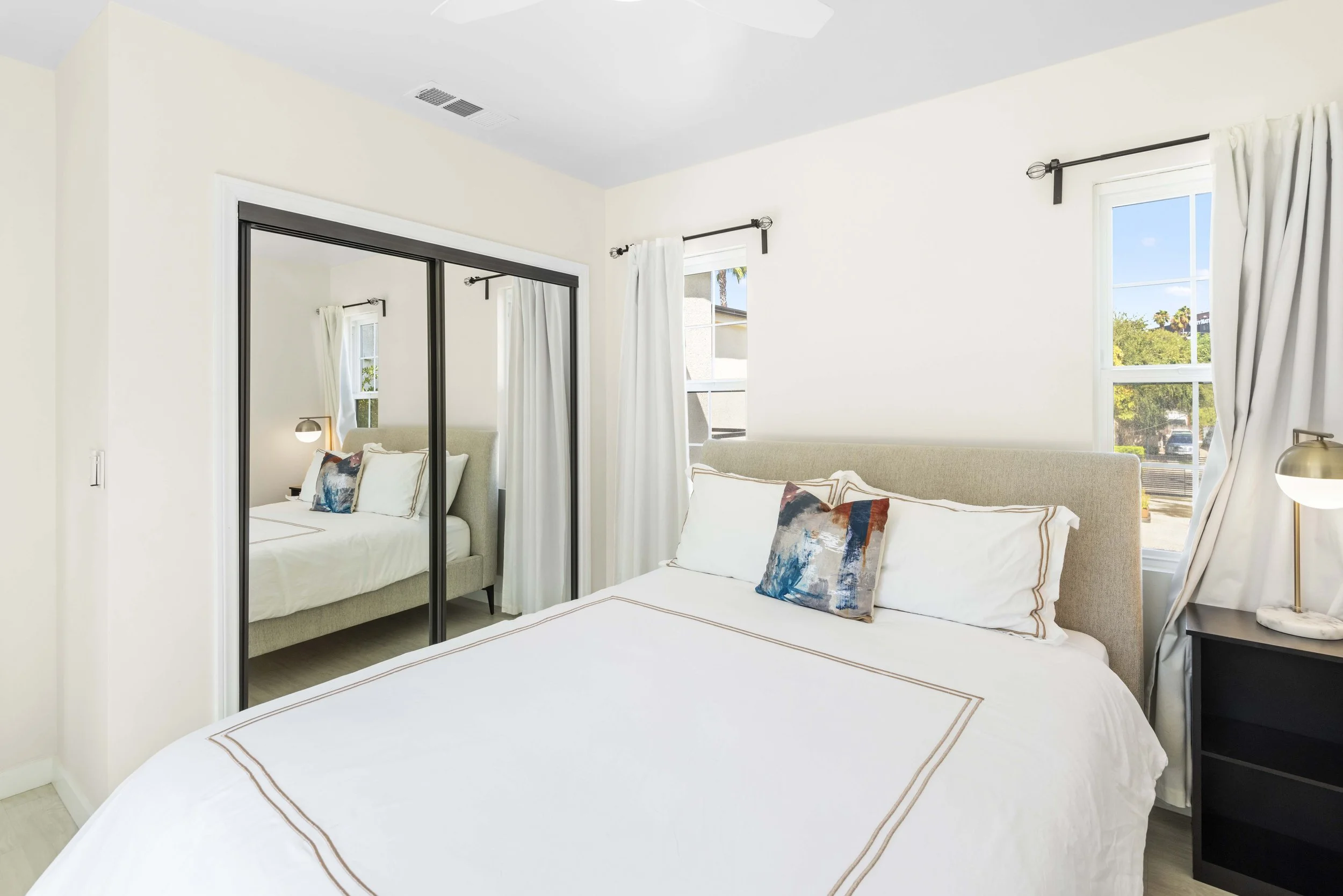 Soft-lit bedroom with mirrored closet and decorative pillows – affordable real estate photography in Los Angeles by Intuition Real Estate Photography & Imaging.