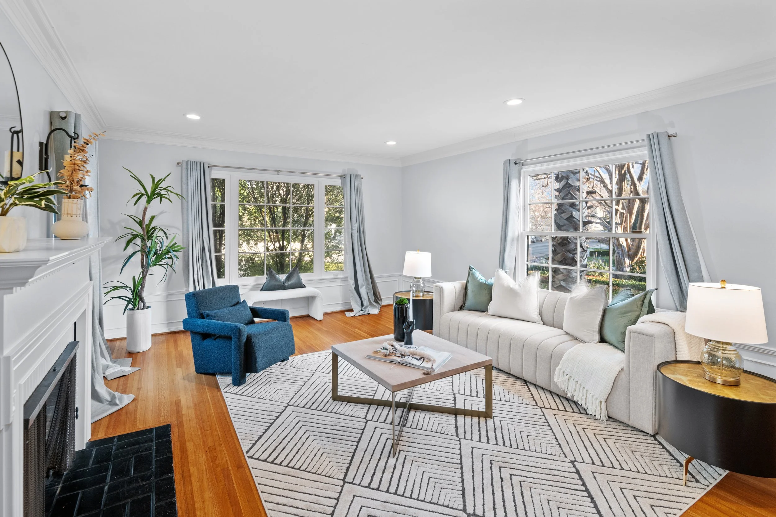 Bright living room with white sofa, blue armchair, hardwood floors, and large windows — interior photo by Intuition Real Estate Media serving Los Angeles homes.