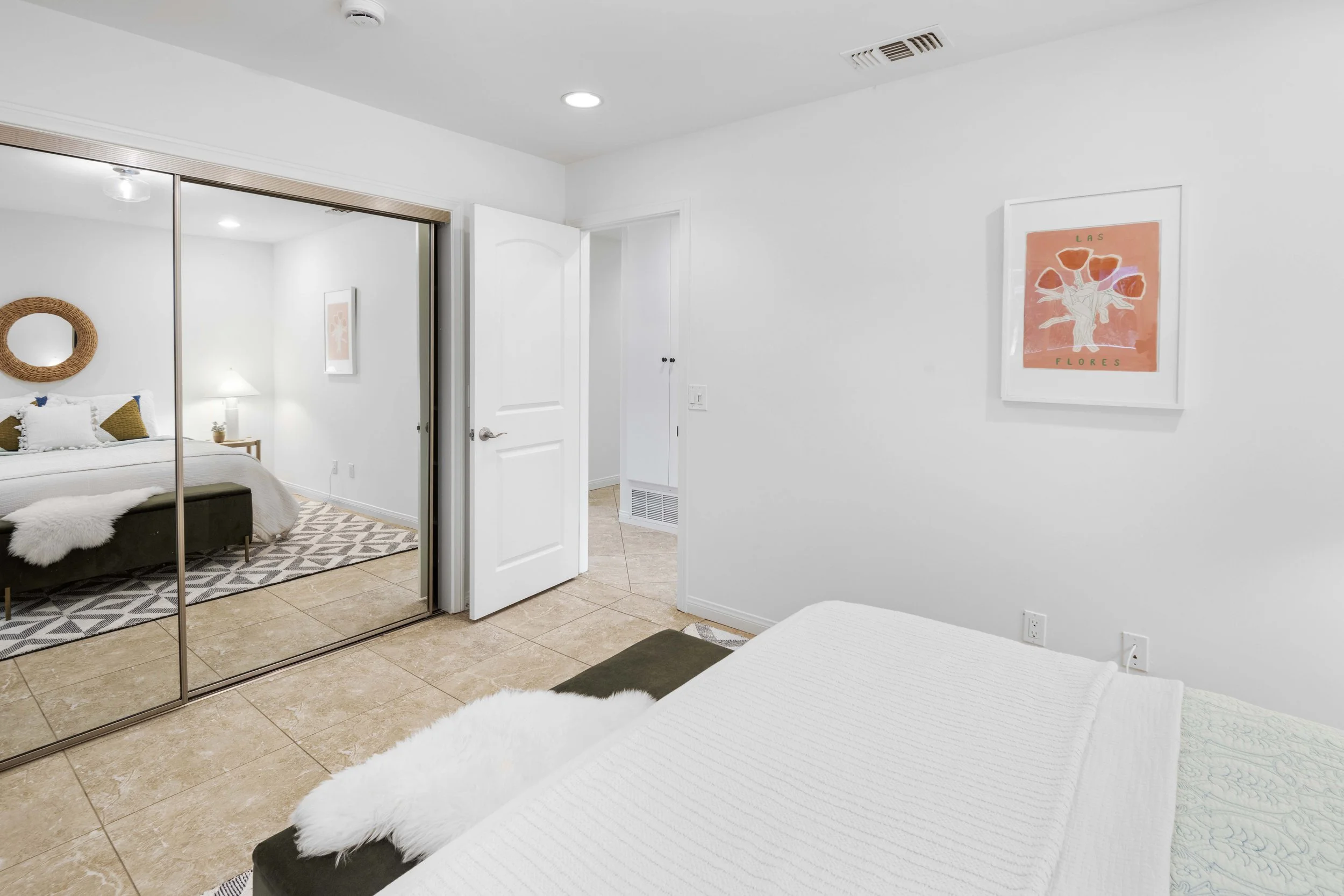 Los Angeles bedroom with white bedding, tan tile floors, mirrored closet doors, and clean staging — affordable real estate photography by Intuition Real Estate Media.