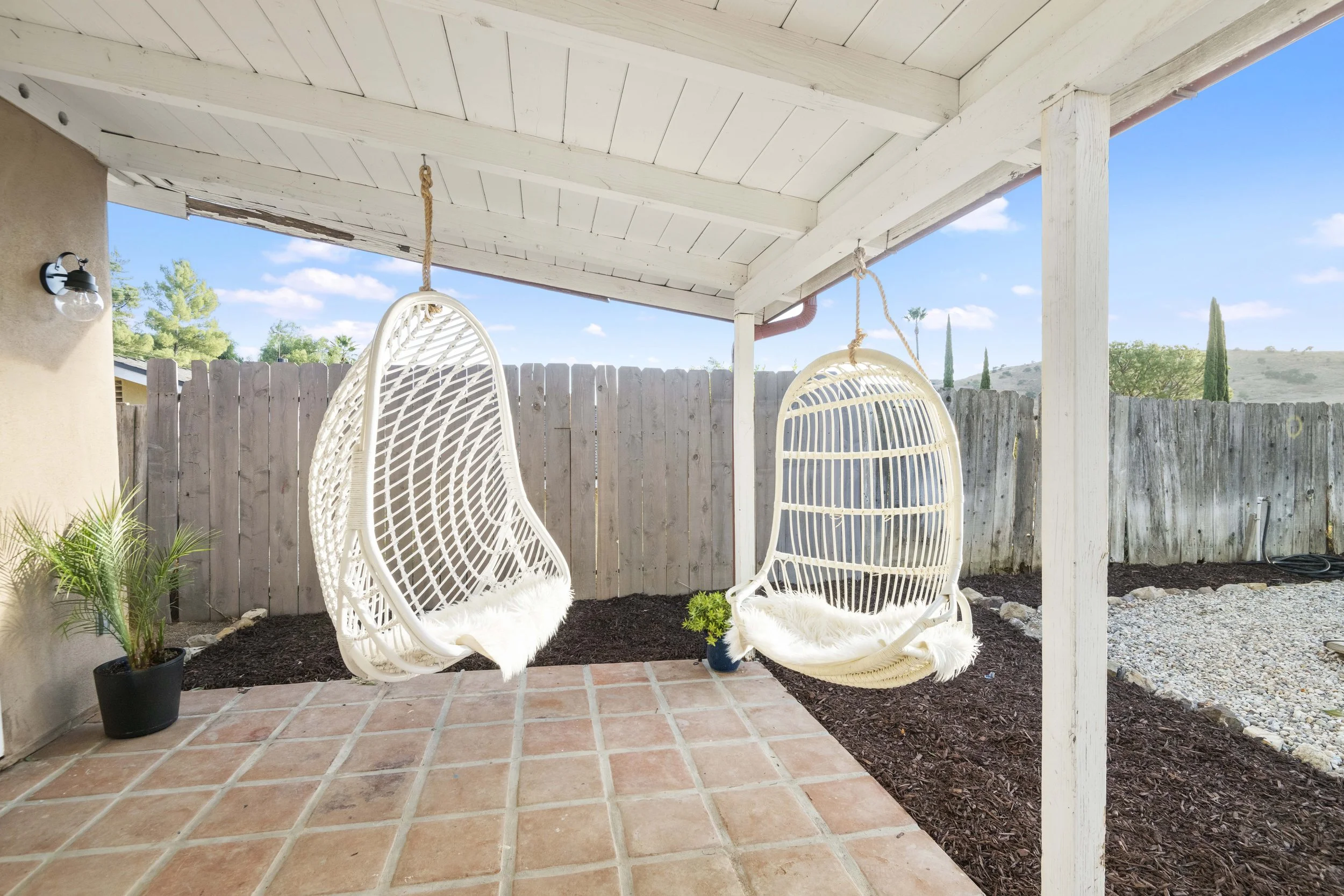 Outdoor porch with white egg chairs and potted plants, photographed in Los Angeles by Intuition Real Estate Photography & Imaging — perfect for showcasing lifestyle listings.