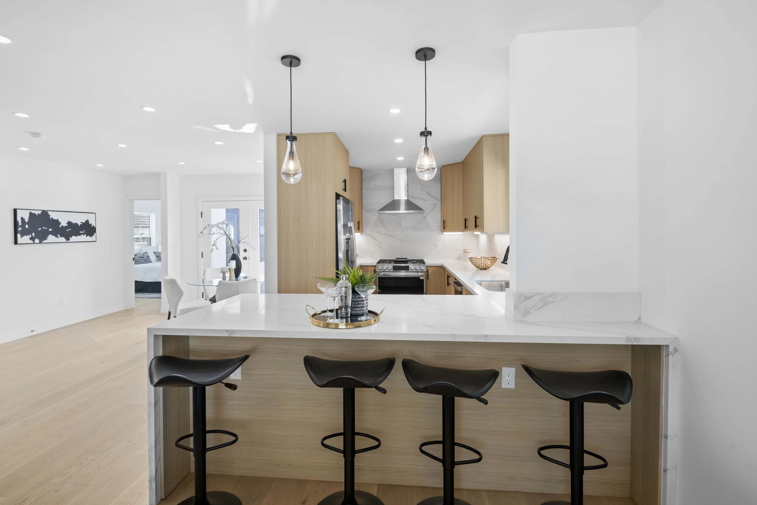 Elegant Los Angeles kitchen with black bar stools, marble counters, and stylish staging — ideal for upscale listing presentations by Intuition Real Estate Media.