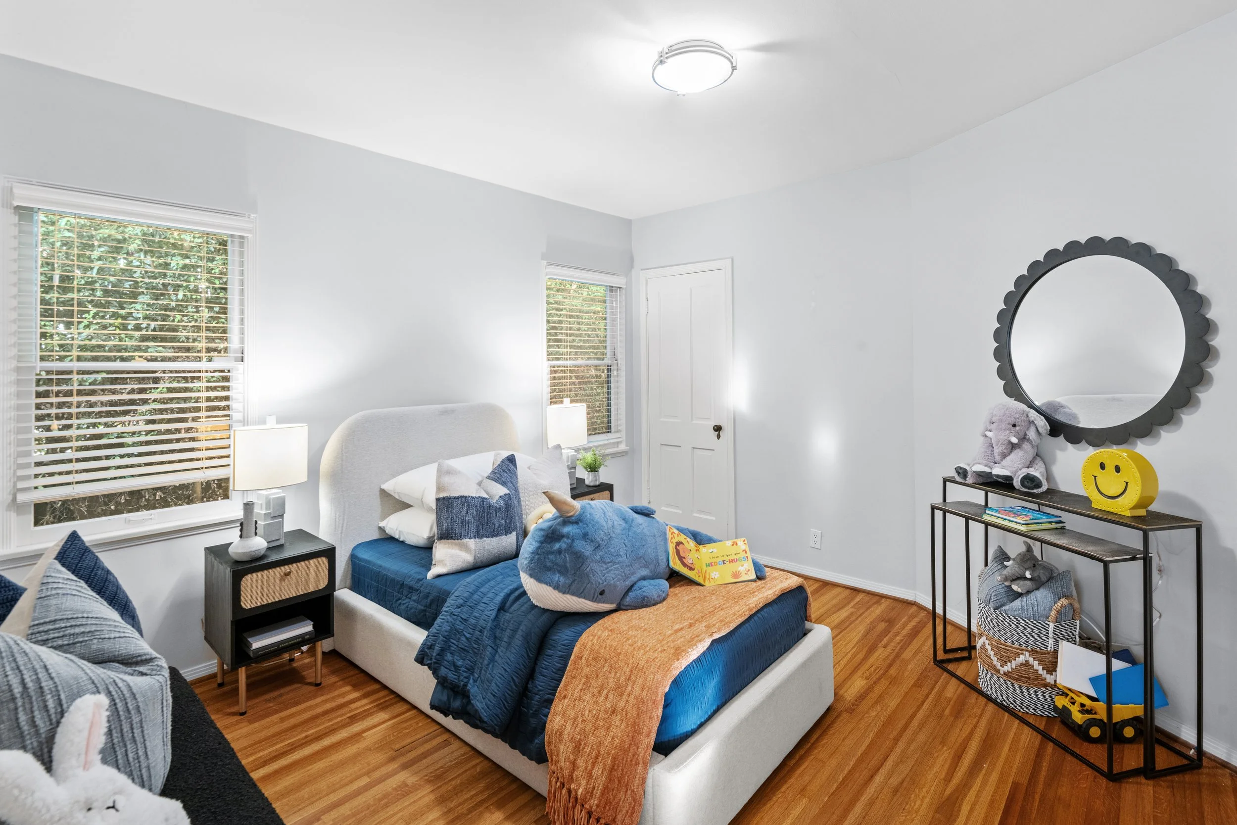 Kid-friendly bedroom with plush whale toy, white bed, blue bedding, and hardwood floors — playful and stylish listing photo by Intuition Real Estate Media, Los Angeles.