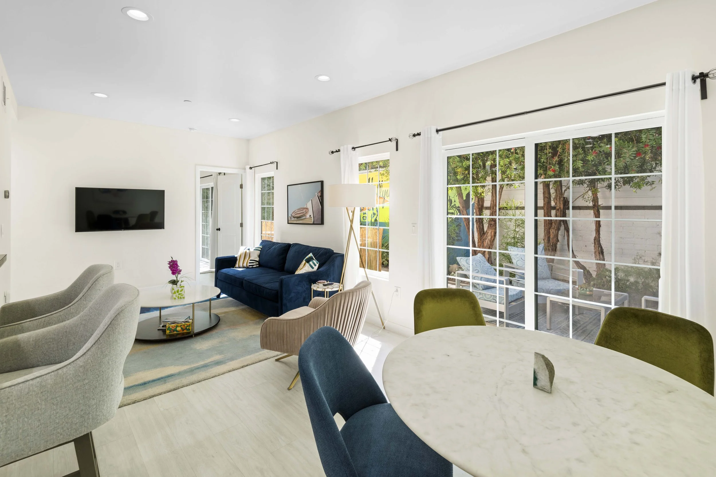 Modern Los Angeles living room with stylish seating and tree-lined patio view — high-quality real estate photo by Intuition Real Estate Media for Zillow, Redfin, or MLS exposure.