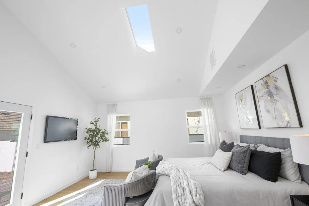 Bright Los Angeles bedroom with skylight and potted plant – real estate photography by Intuition Real Estate Photography & Imaging with modern staging.