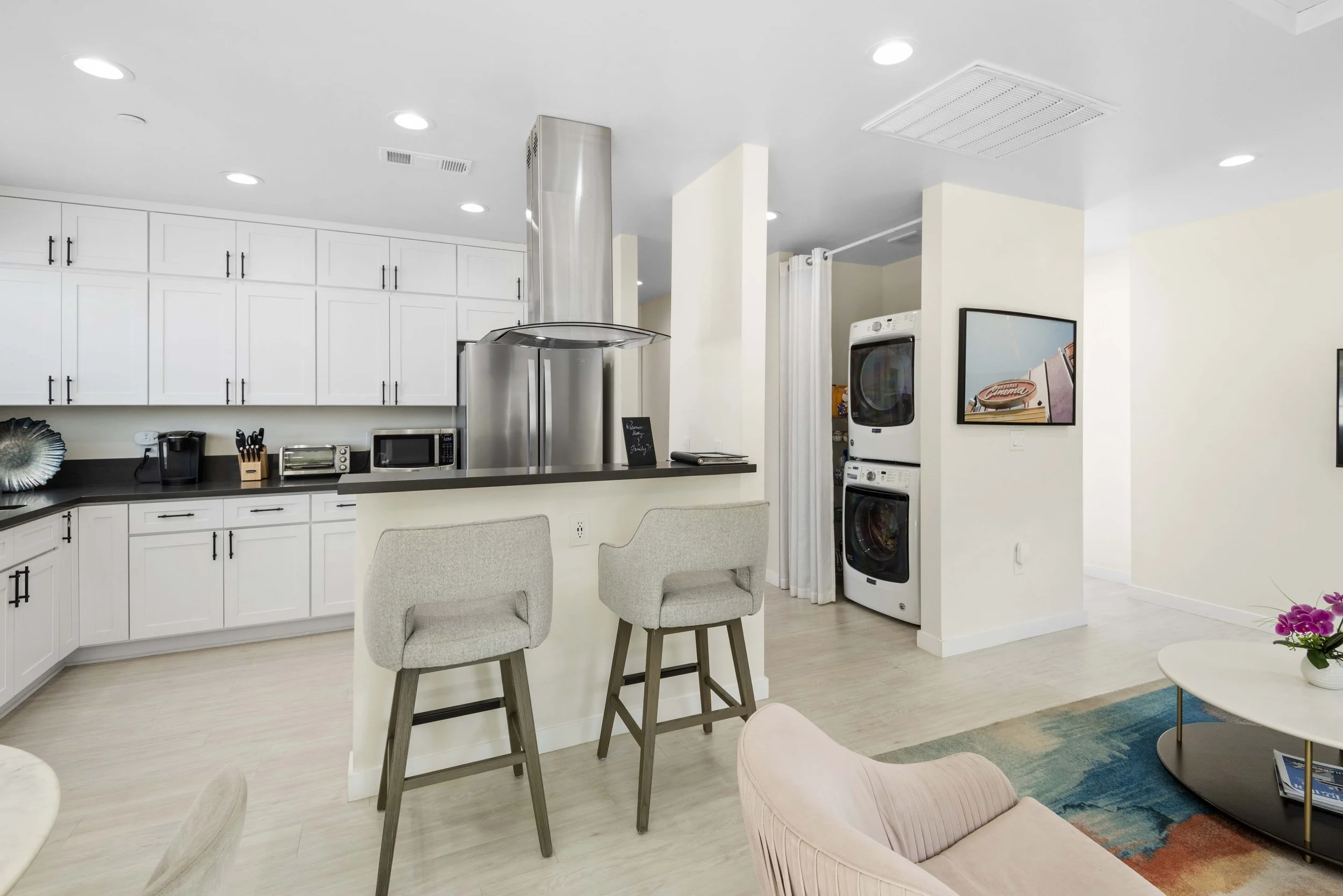 Modern Los Angeles kitchen with laundry area and breakfast bar – black countertops and white cabinetry captured by Intuition Real Estate Media for efficient home listing photography.