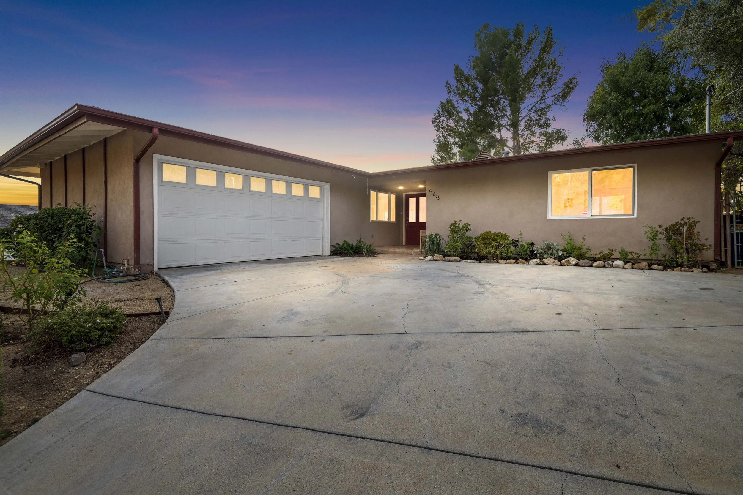 Sunset view of LA single-story home with two-car garage, landscaped walkway, and concrete driveway — affordable twilight shoot by Intuition Real Estate Media.