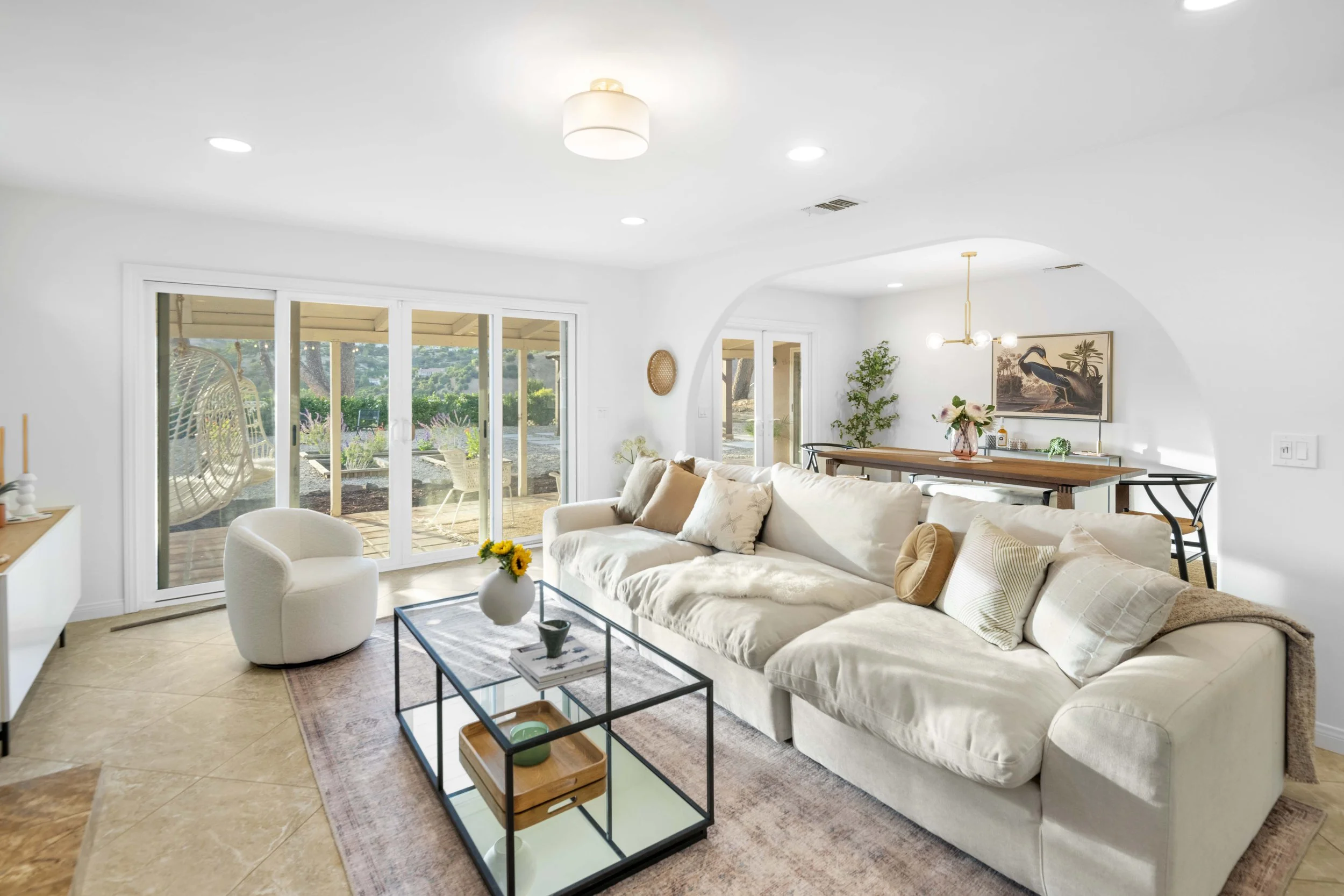 Spacious Los Angeles living room with white sofa, glass coffee table, and patio access — photographed by Intuition Real Estate Media for premium listing presentation.
