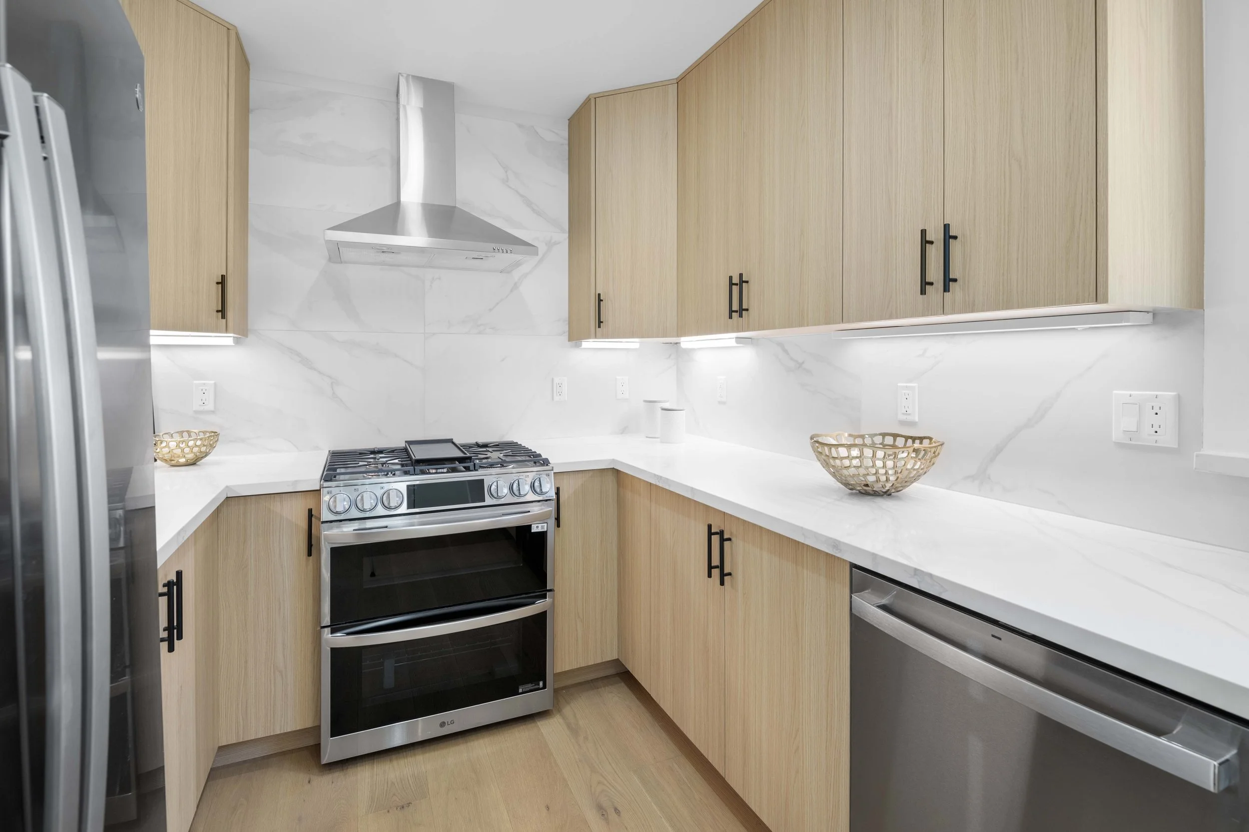Modern kitchen with wood cabinets, stainless steel appliances, and marble counters — expertly photographed by Intuition Real Estate Media in Los Angeles.