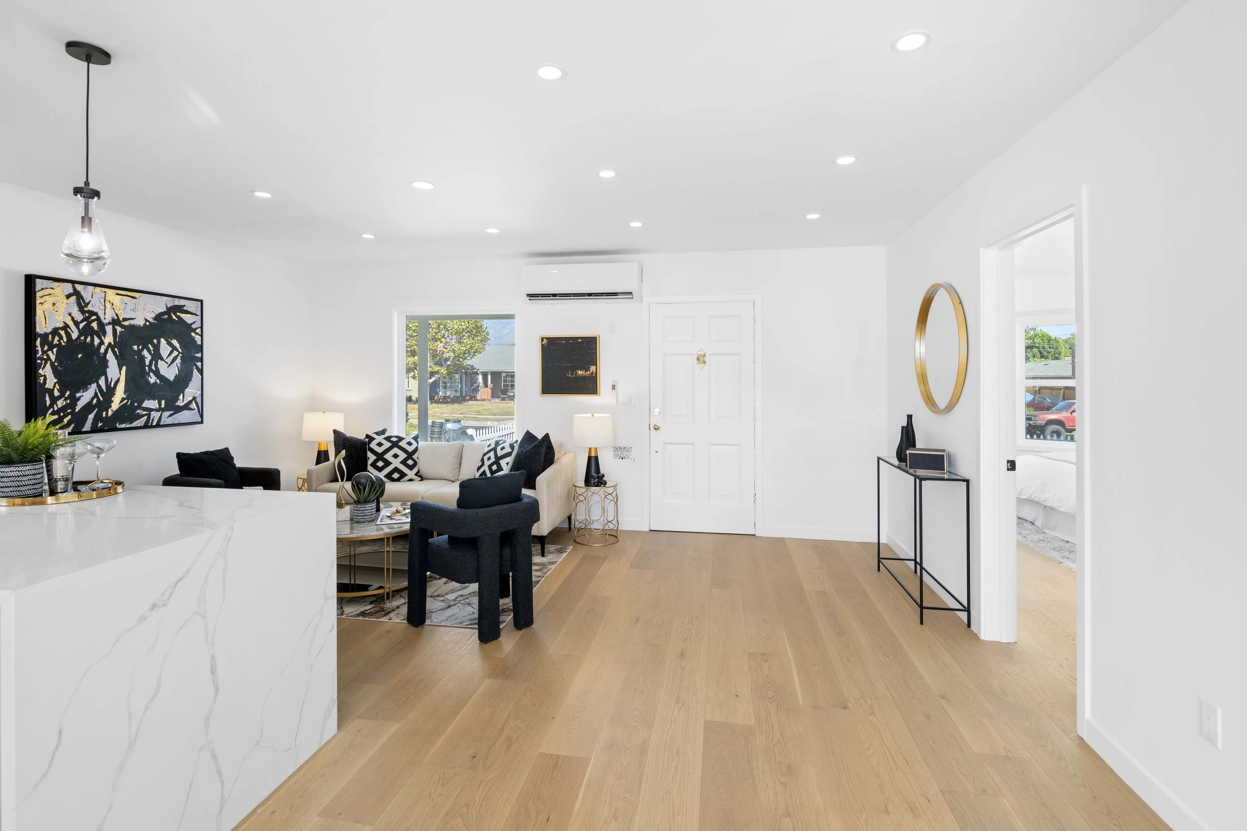 Warm Los Angeles living room with beige sofa, black and white armchairs, hardwood floors, and sliding glass doors — professional real estate photography by Intuition.