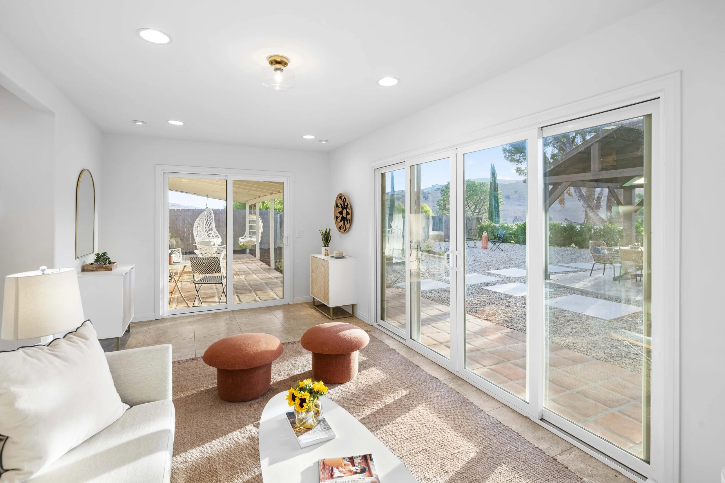 Scenic LA living room with large sliding doors, swing chairs, and hillside views — captured by Intuition Real Estate Media for stunning lifestyle property visuals.