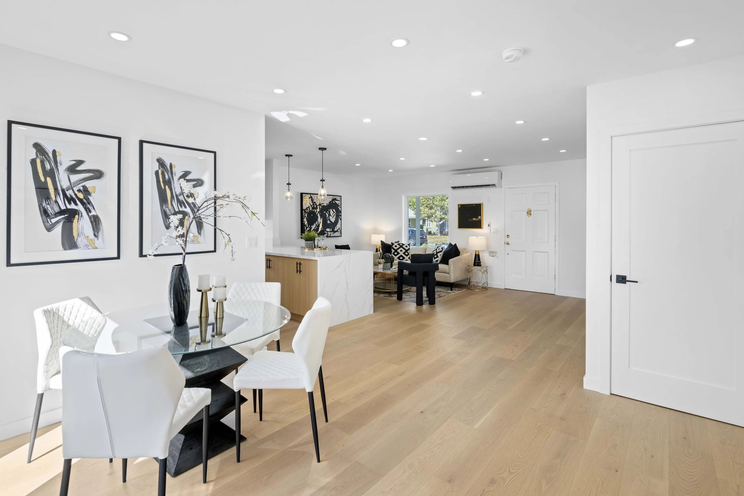 Minimalist Los Angeles living and dining area with modern furniture, white walls, and abstract art — high-end real estate image by Intuition.