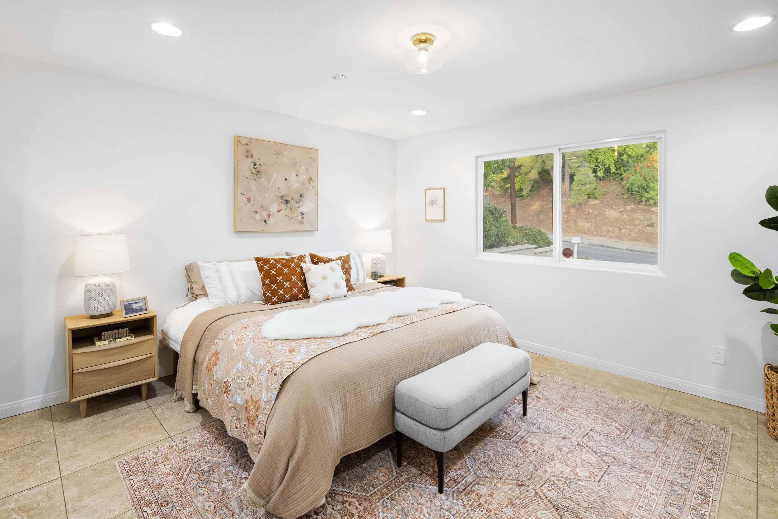 Sunlit bedroom with neutral bedding, twin nightstands, and indoor greenery — LA property photo by Intuition Real Estate Media for inviting, organic lifestyle marketing.
