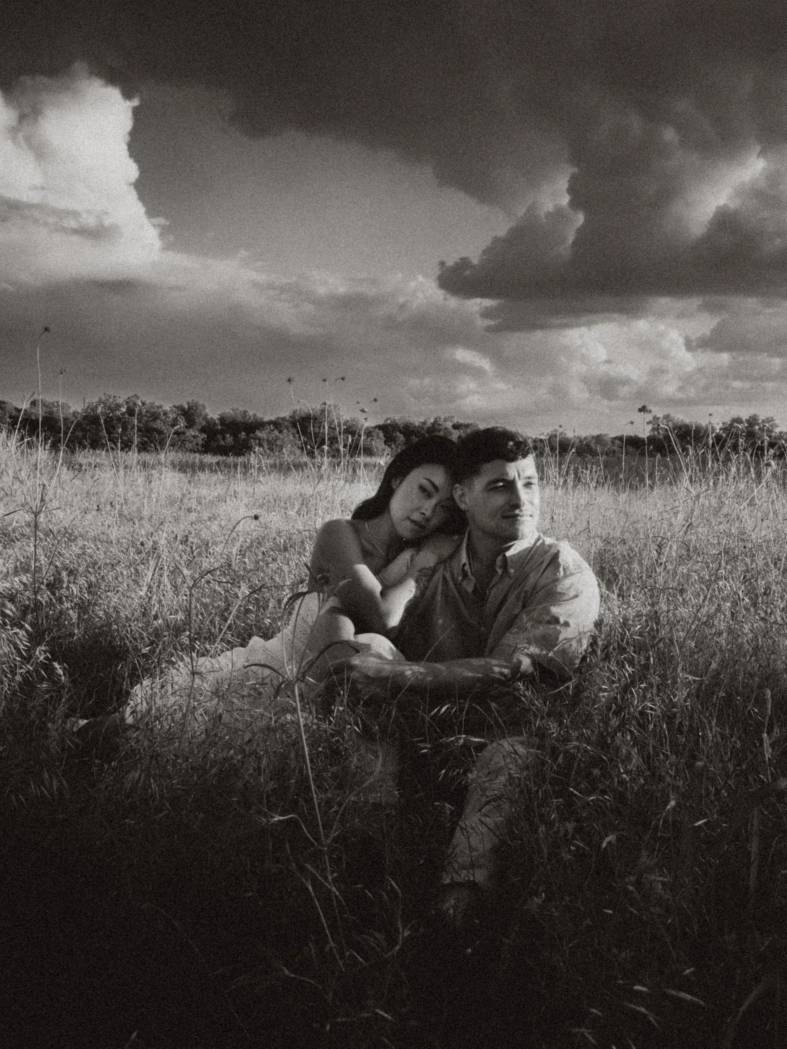  Grainy black and white lifestyle photography of a couple sitting in tall grass at  Erwin Park in McKinney . 