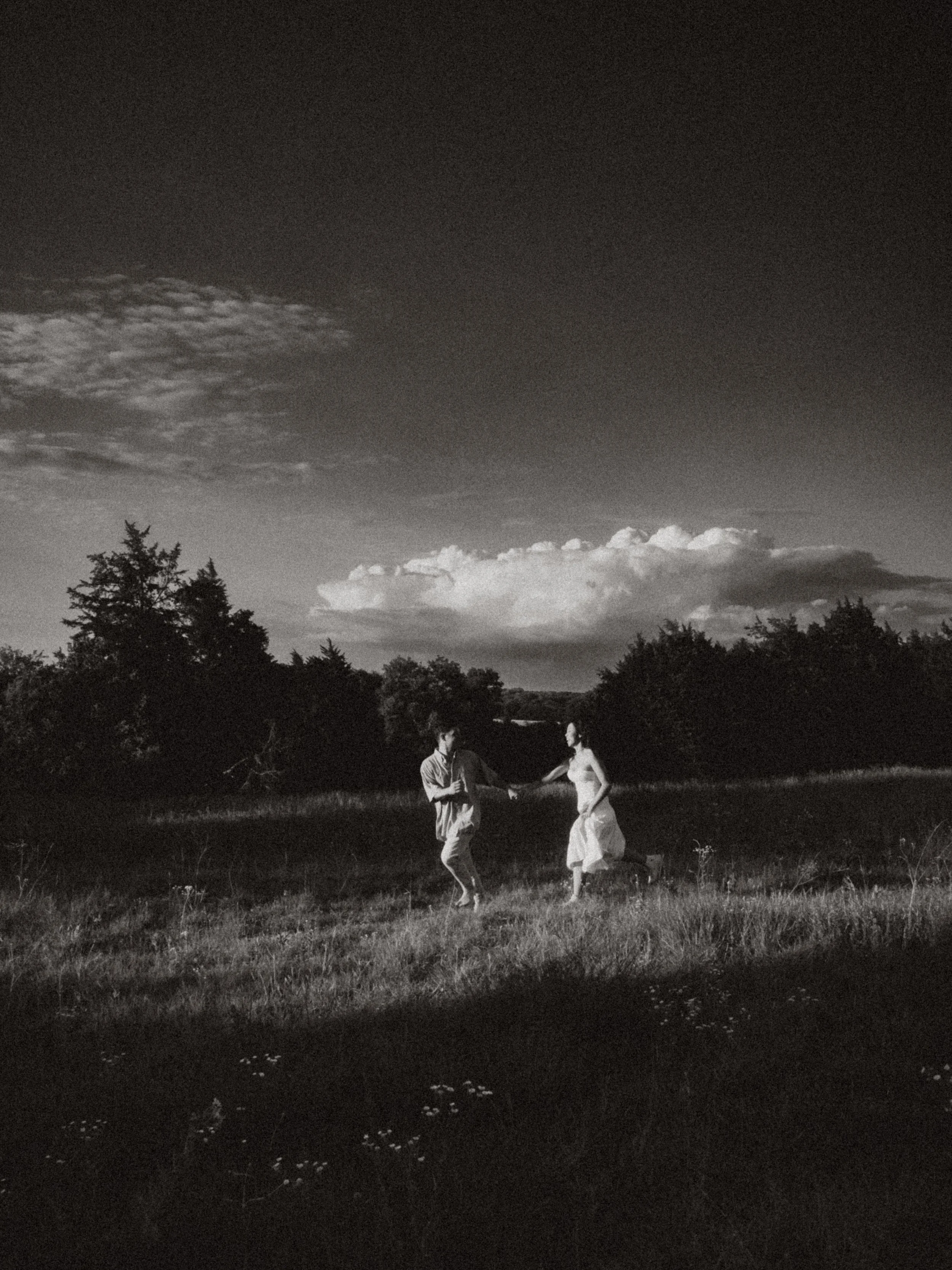  B&amp;W motion-blur photography of a couple running hand-in-hand through an open meadow at  Erwin Park in McKinney . 