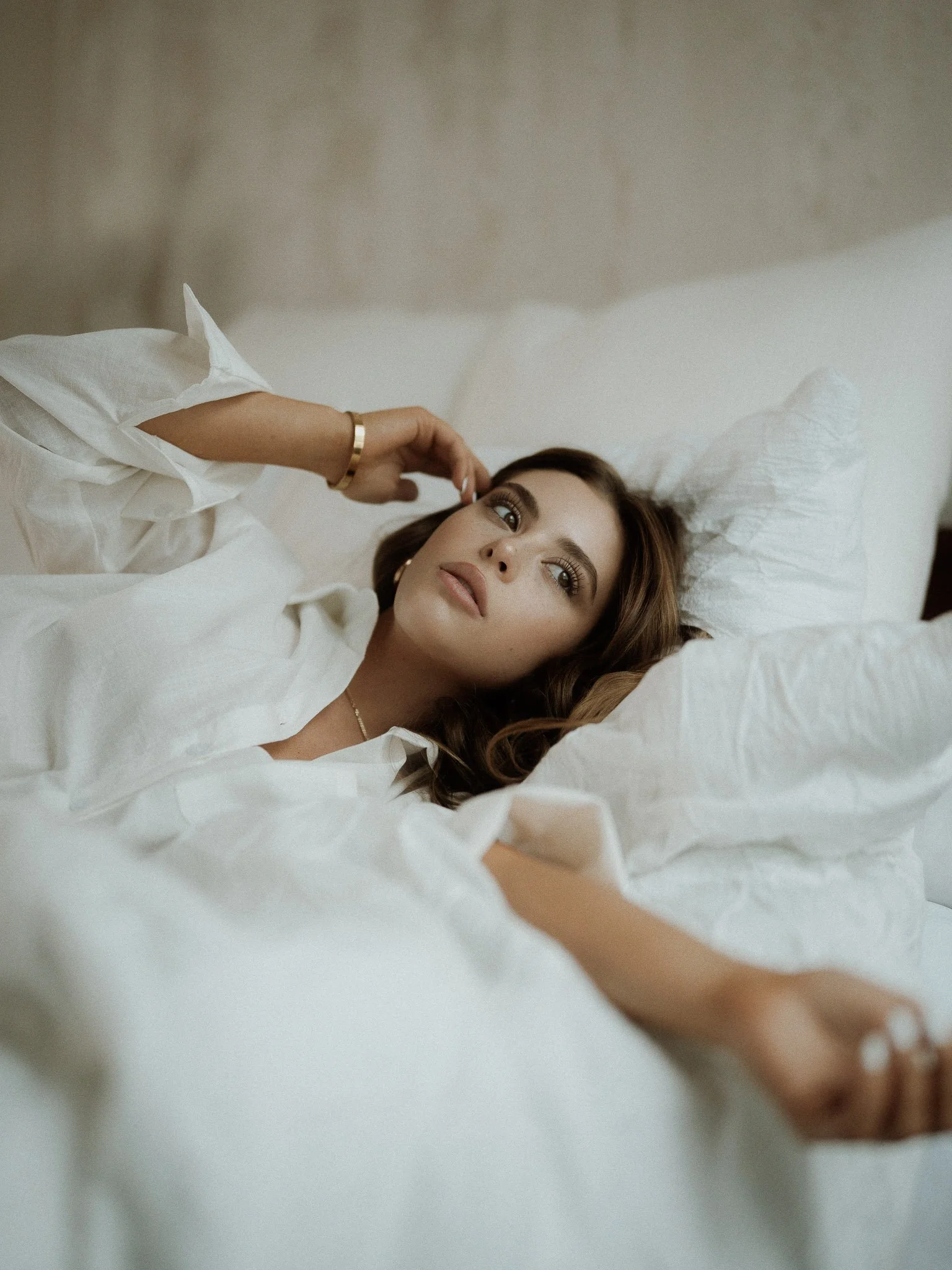 Dallas, Texas modeling session featuring a model laying on a bed while looking out the window. The photo has a dreamy aesthetic.