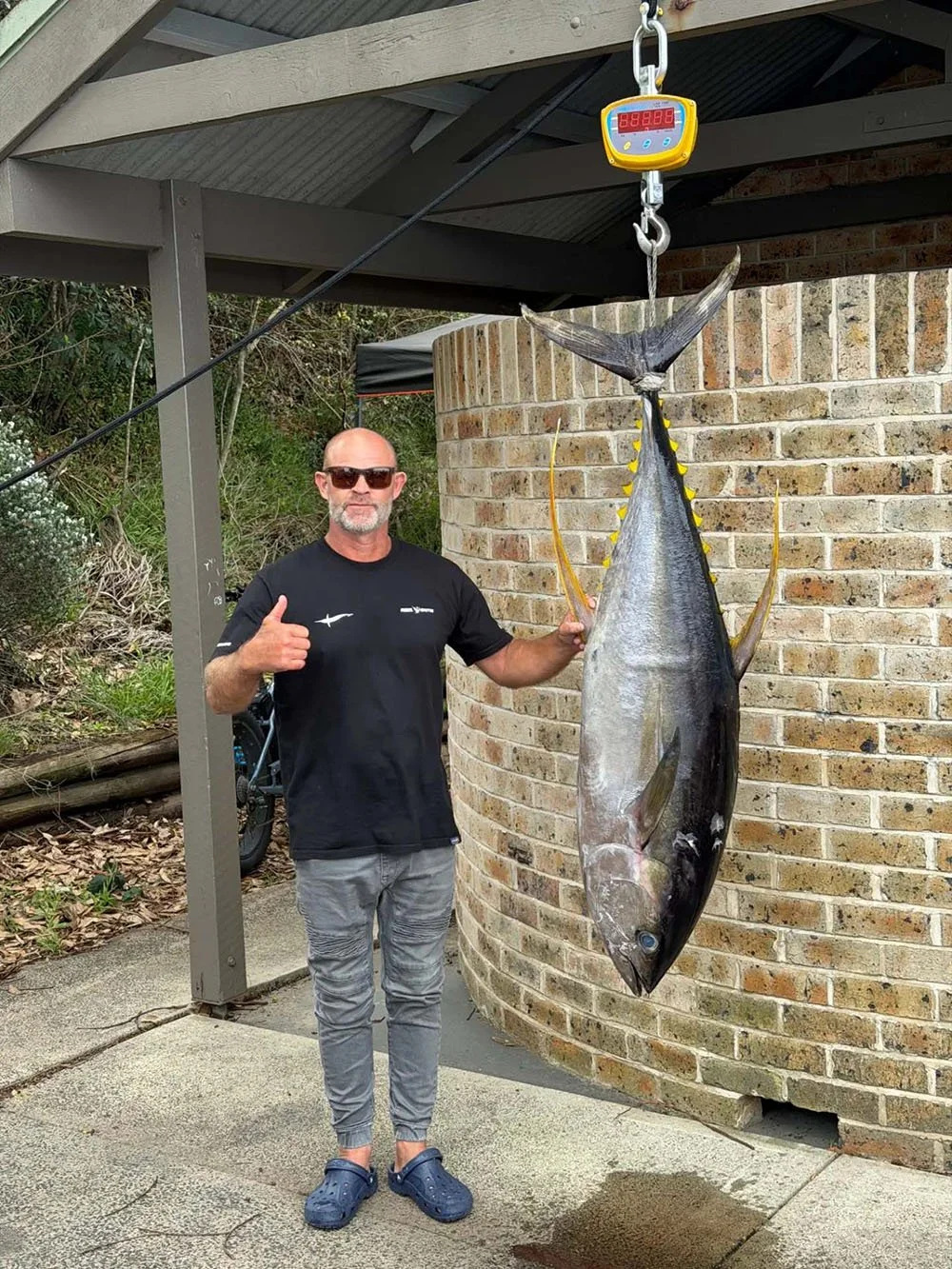 Heads Fishing Club member Dan Corr standing next to a large tuna on a digital scale at Carters Corner.