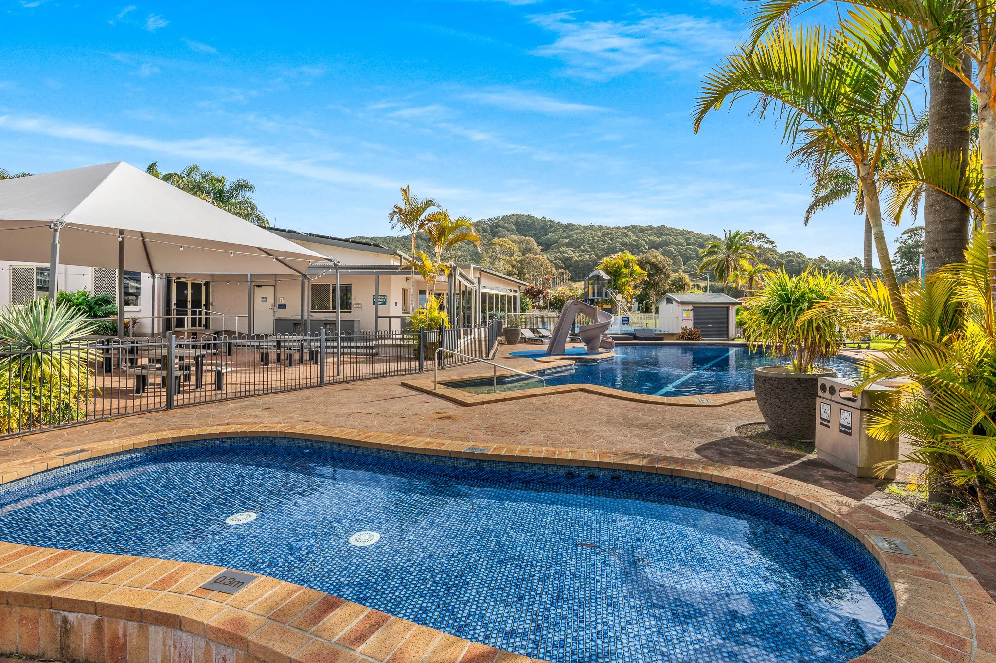 Outdoor pool area with water slide, shaded dining terrace and lush tropical landscaping at Mountain View Resort