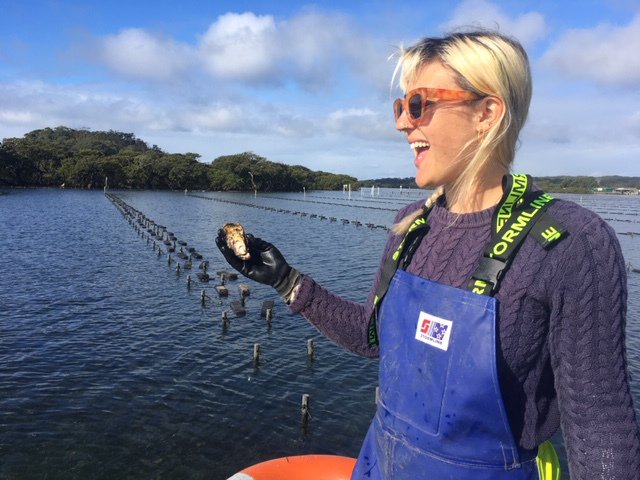 Woman holding a freshly harvested Sydney Rock oyster on the Bel's Oysters farm, Greenwell Point