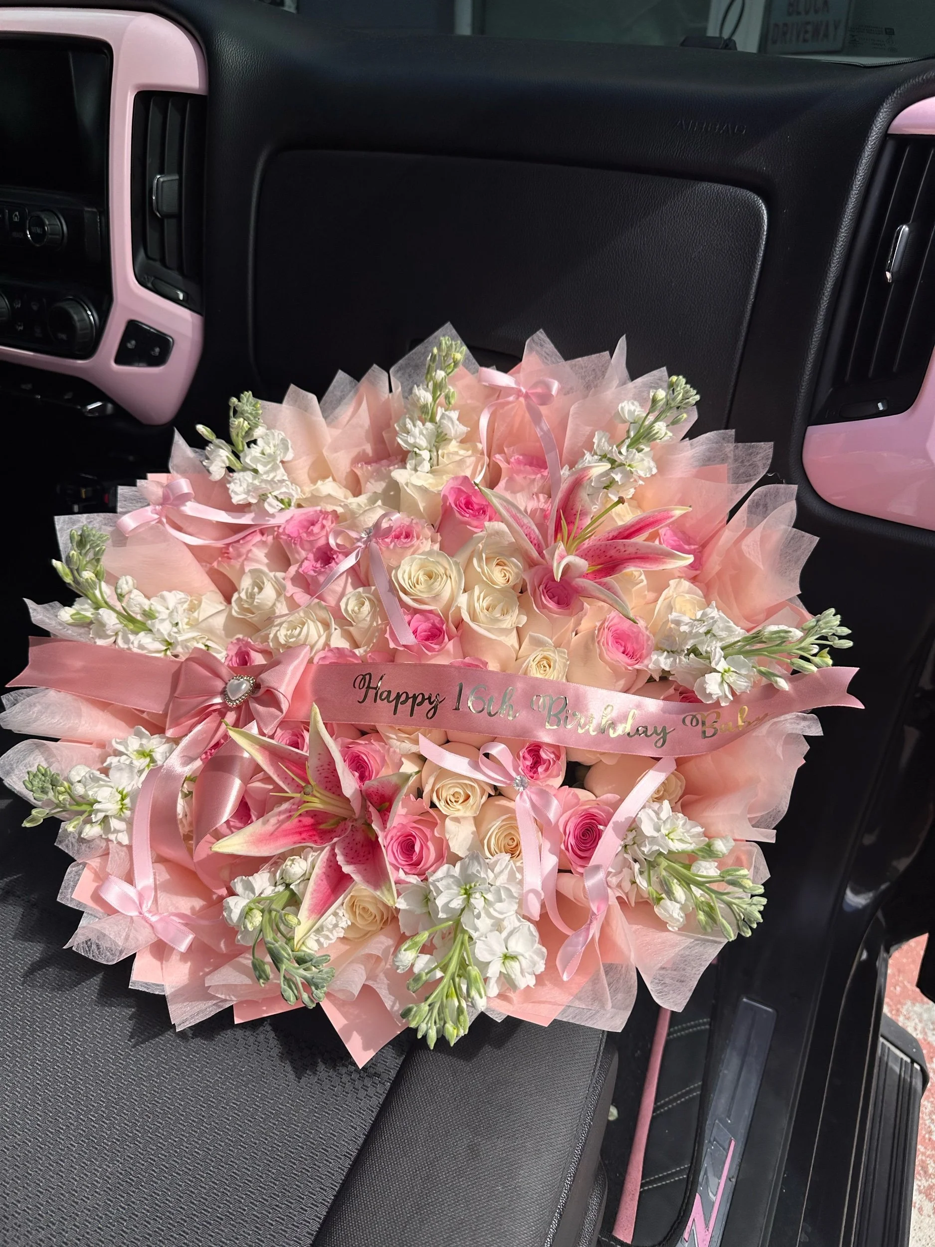 Pink and white rose bouquet with white stock, lilies, pink tissue, and a custom message banner.