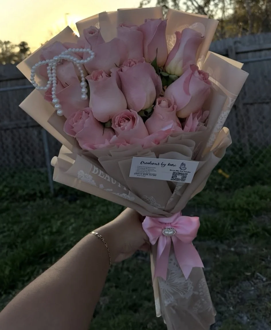 Pink rose bouquet with a pearl bow, wrapped in brown butterfly-patterned floral paper.