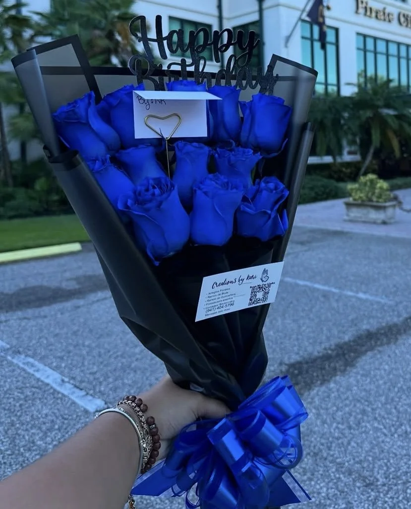 Blue rose bouquet with a custom message topper, wrapped in transparent black floral paper with a black border.
