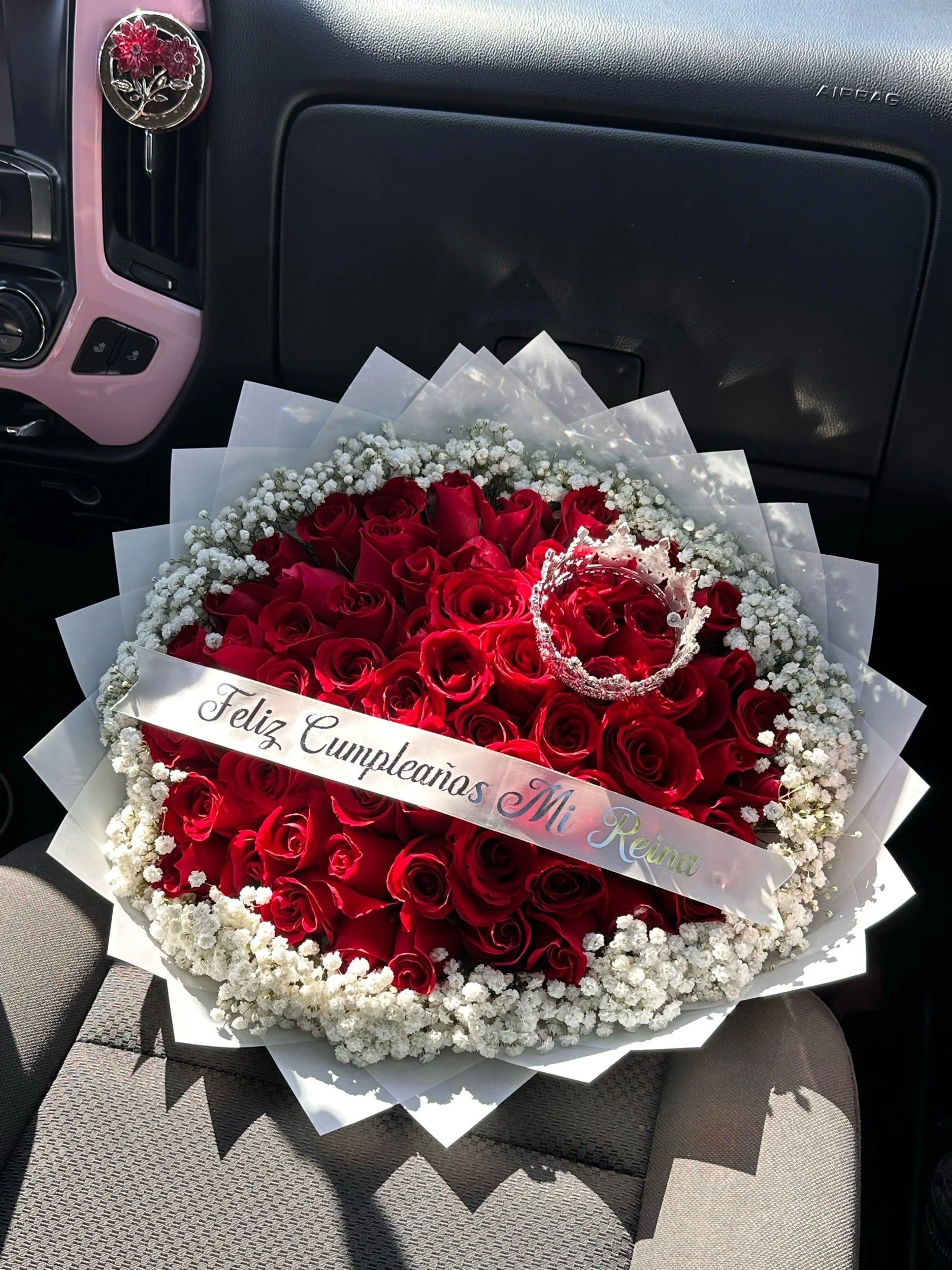 Red rose bouquet with a baby’s breath border, message banner, and decorative crown.