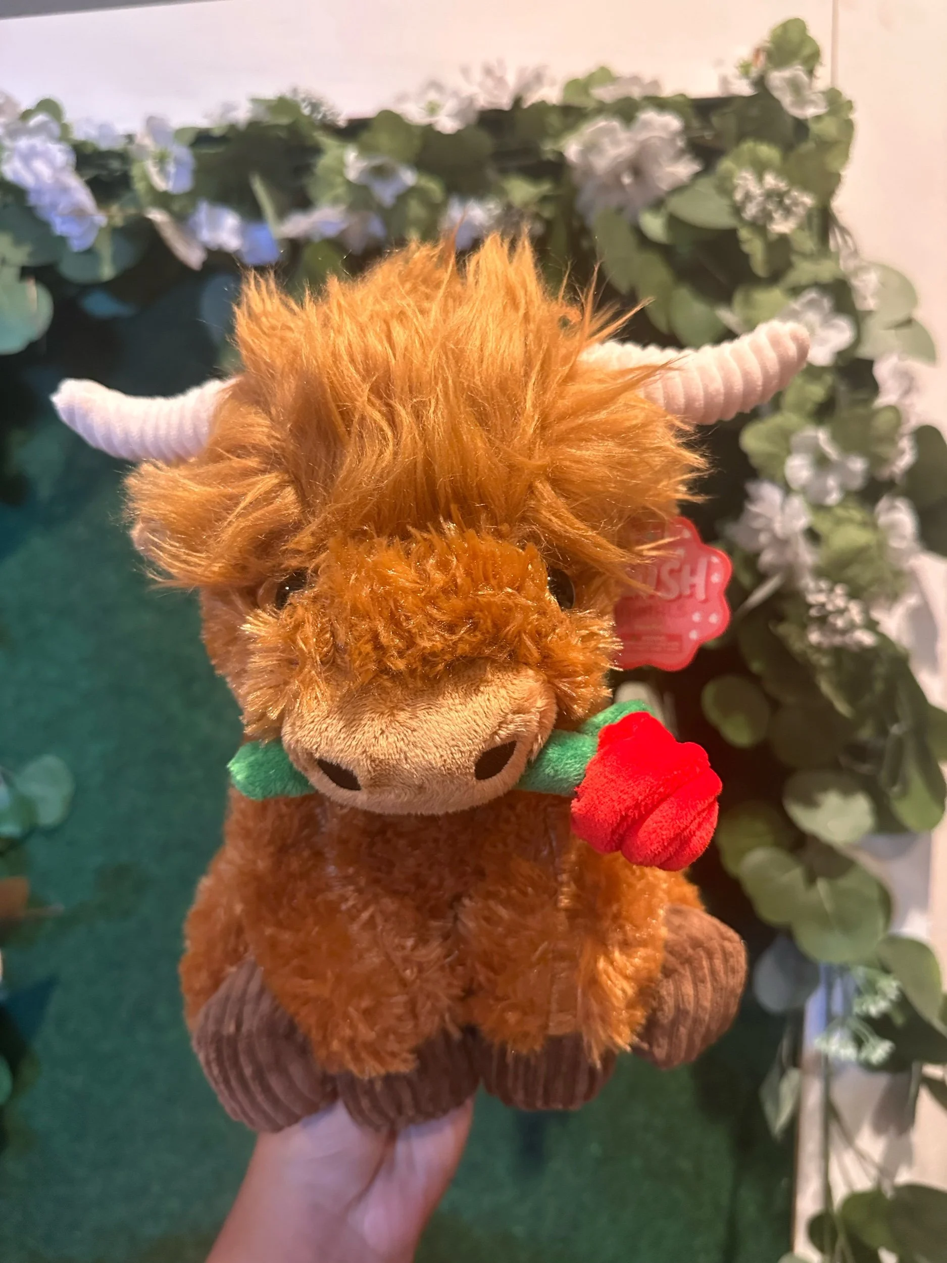 Romantic Brown Highland cow holding a rose from its mouthplush toy.