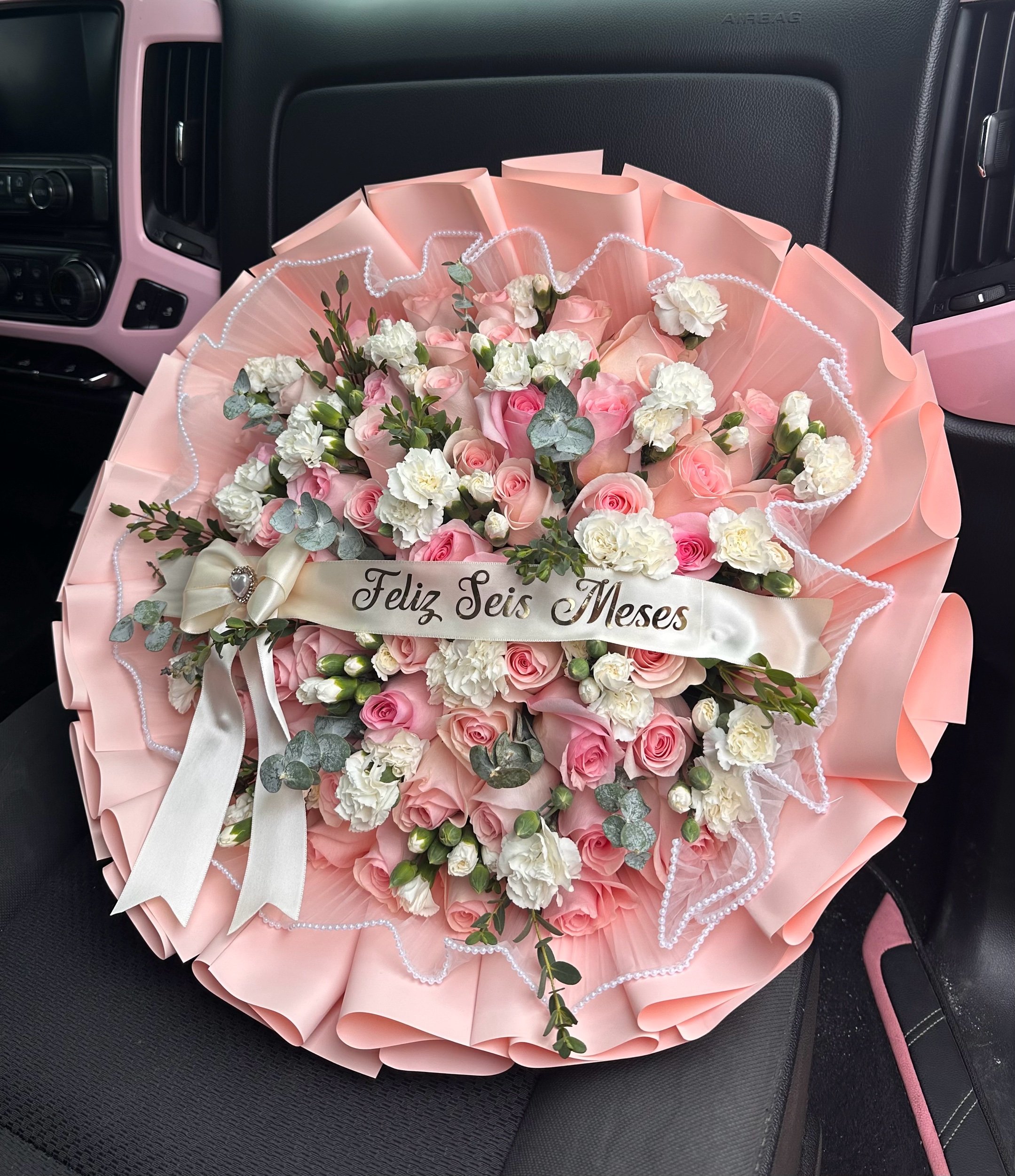 Pink rose bouquet with white mini carnations, eucalyptus, pearl mesh, and pink floral wrapping.