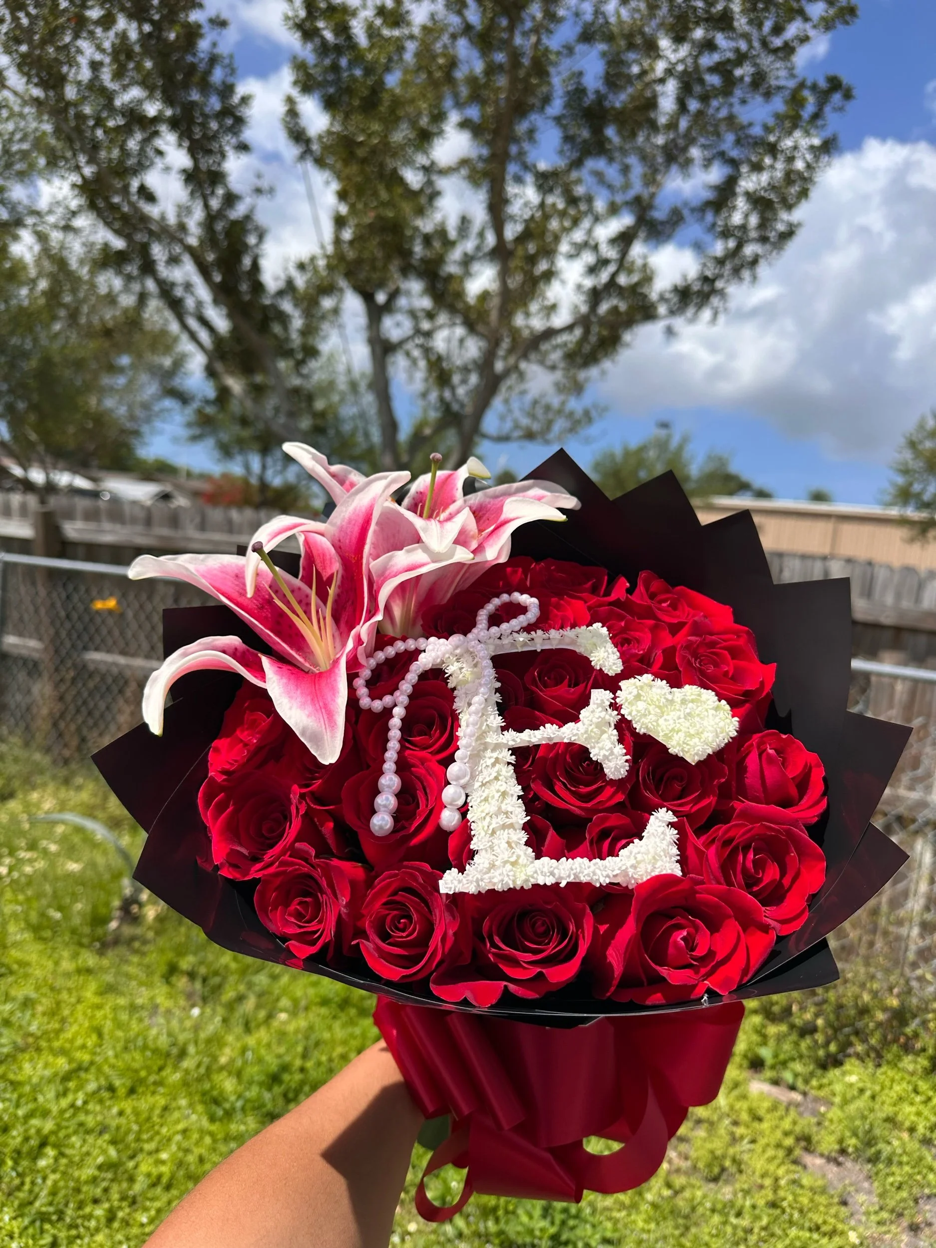 Red rose and lily bouquet with a personalized baby’s breath letter and pearl bow.