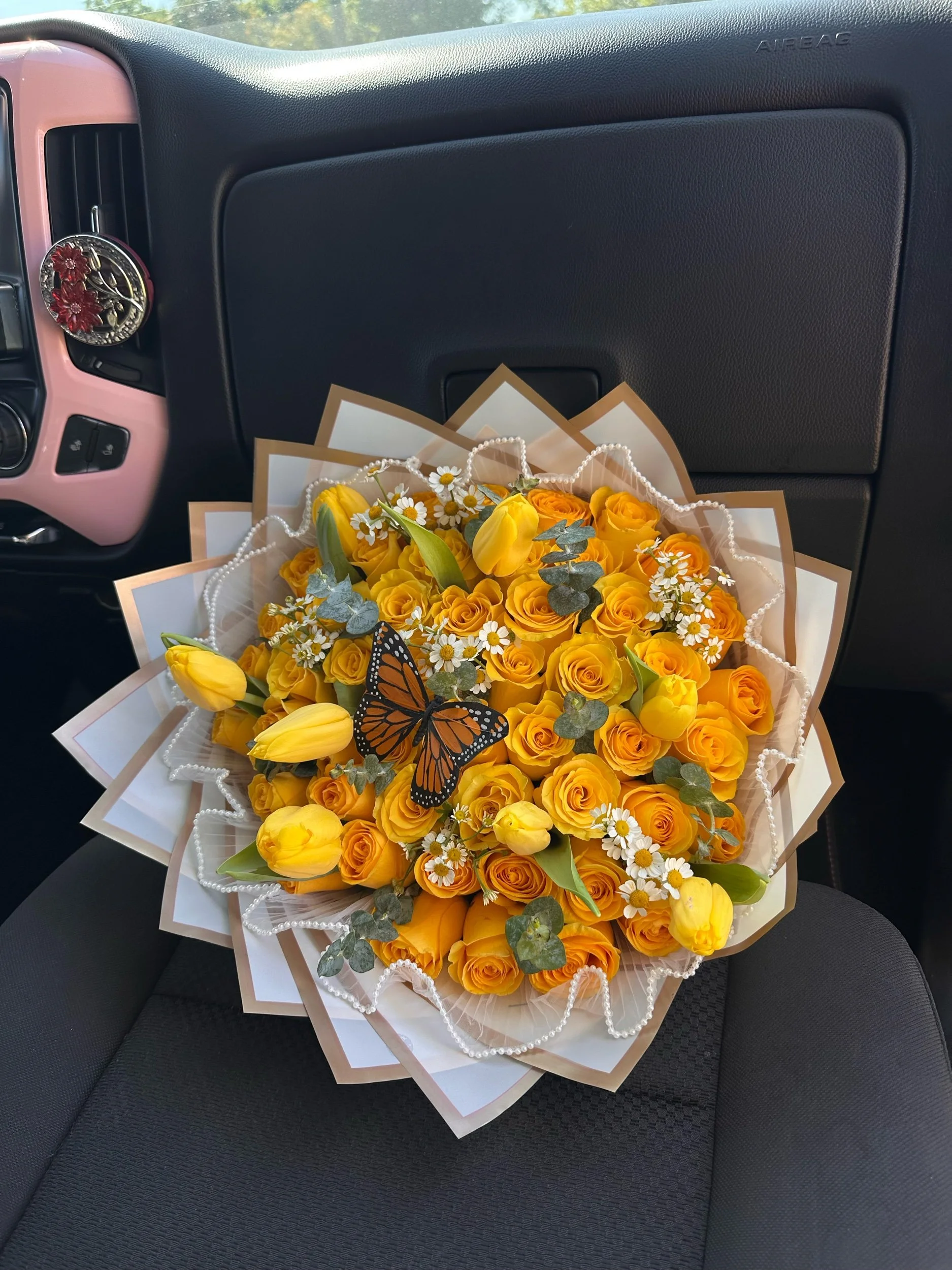 Yellow rose and tulip bouquet with chamomile, baby eucalyptus, a monarch butterfly, pearl mesh, and white floral wrapping with a gold border.