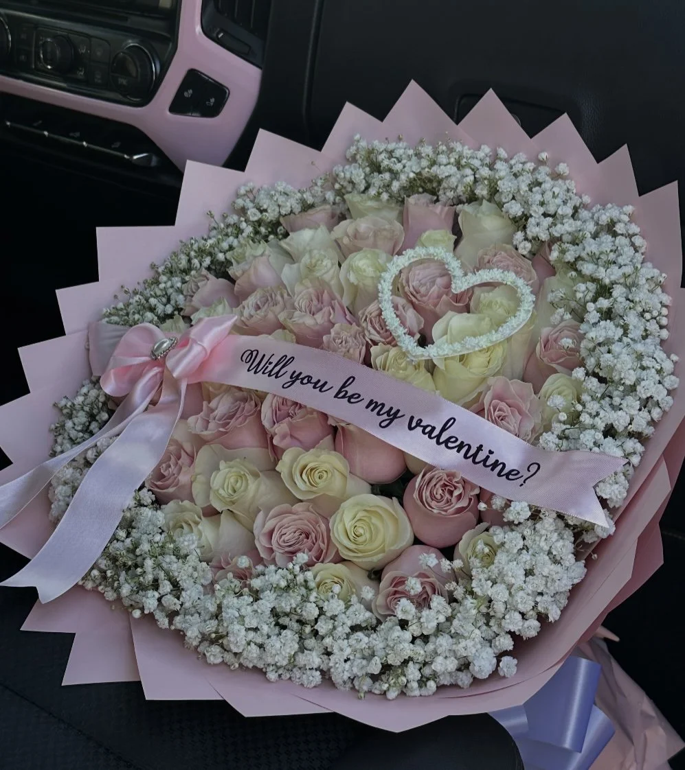 Pink and white rose bouquet with a baby’s breath heart and border, message banner, and pink floral wrapping.