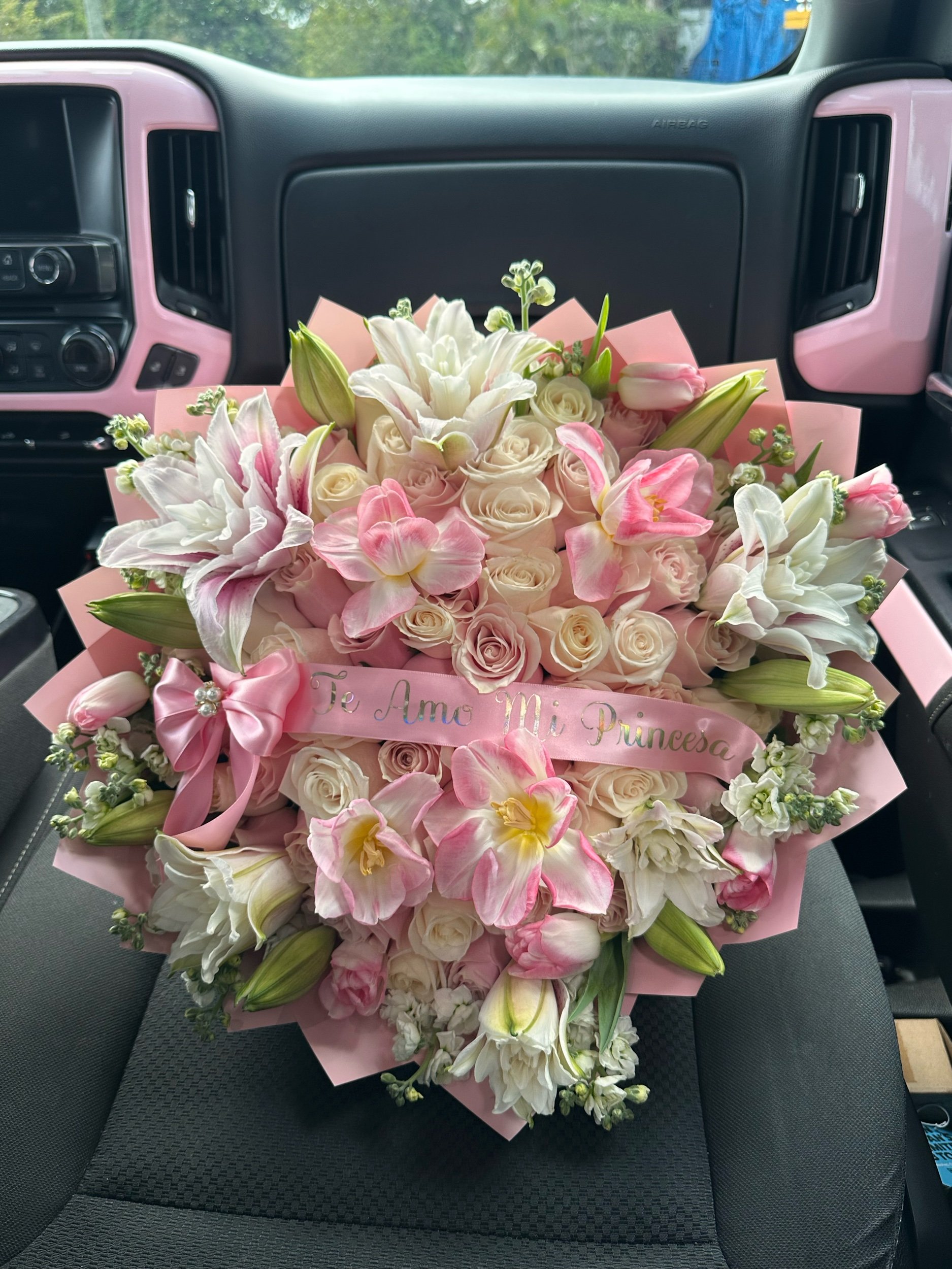 Pink and white rose bouquet with rose lilies, stock, tulips, and a message banner, wrapped in pink floral paper.