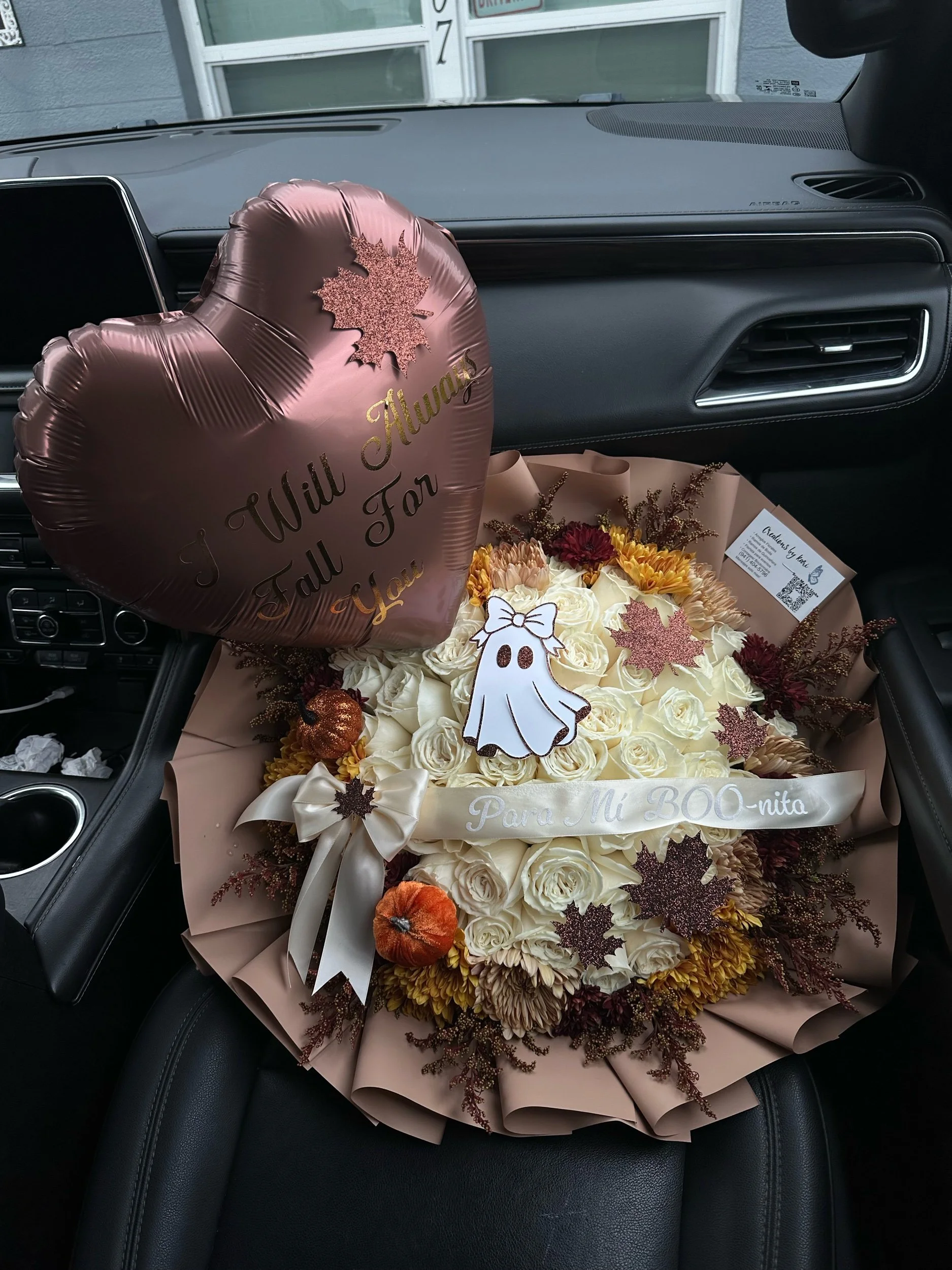 Fall-inspired bouquet with white roses, cremons, poms, astilbe, decorative pumpkins, a ghost topper, and custom message balloon.
