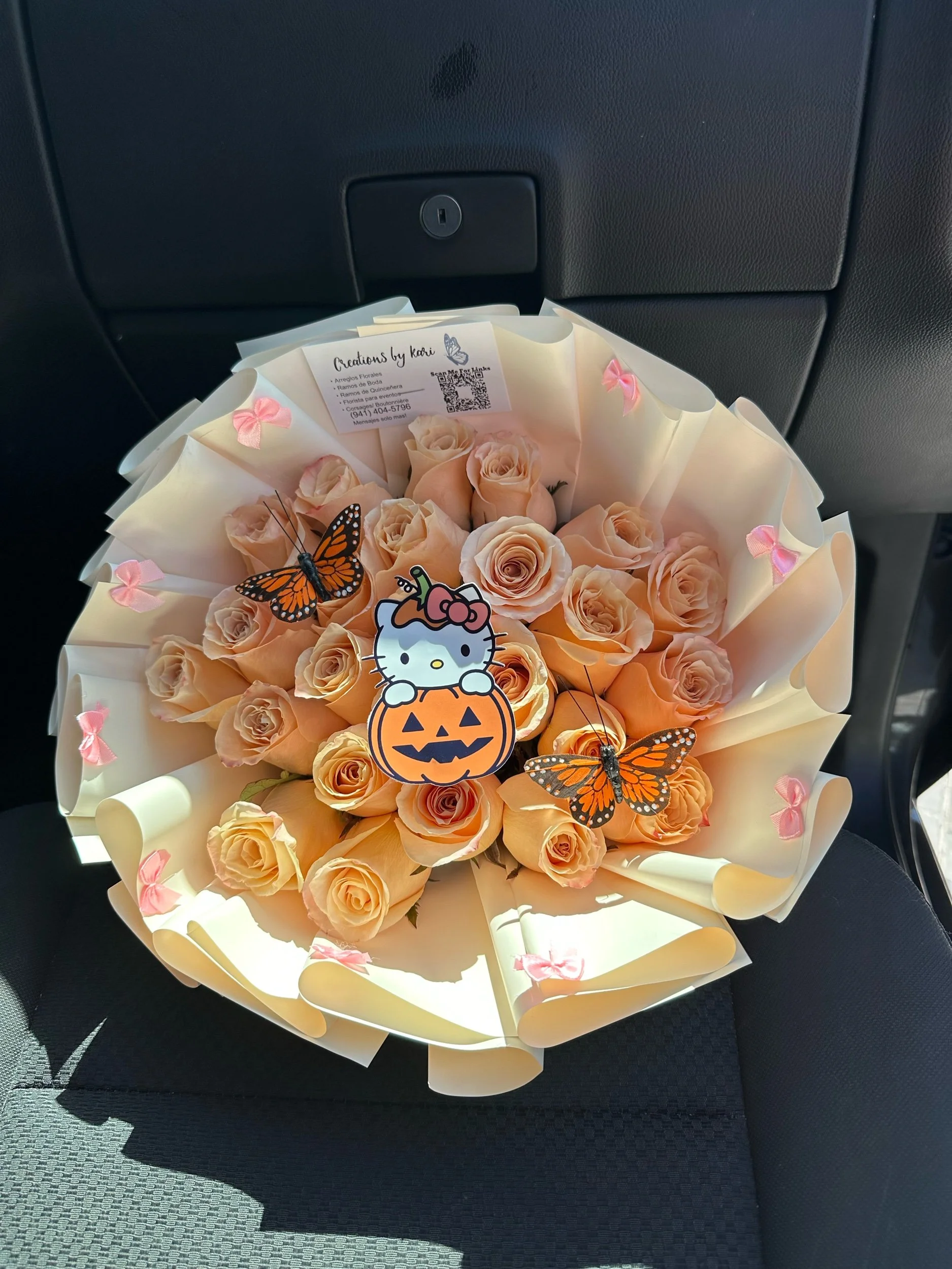 Peach rose bouquet with orange monarch butterflies, Hello Kitty picture toppers, mini pink bows, and white floral wrapping.