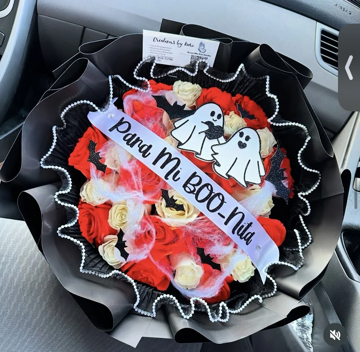 Orange and white rose bouquet with spider-web detailing, pearl mesh, bat and ghost toppers, wrapped in black floral paper.