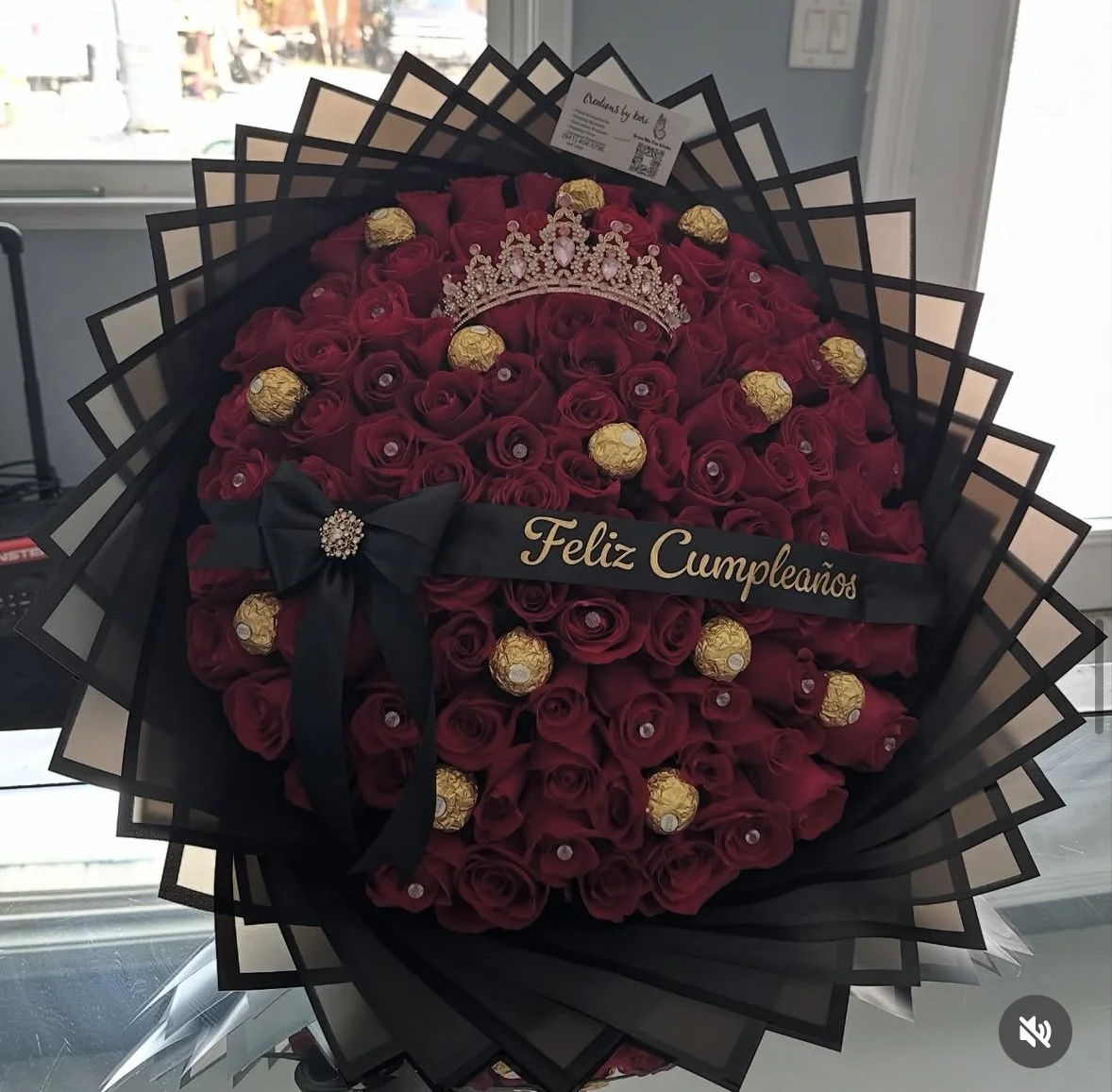 Red rose bouquet with Ferrero Rocher chocolates, a crown, diamond accents, and transparent black floral wrapping.