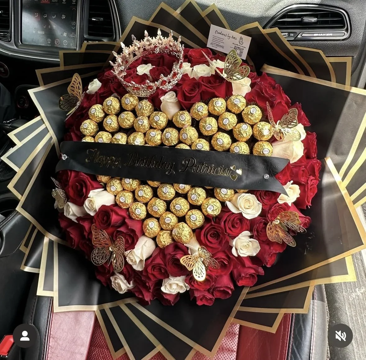 Red and white rose bouquet with a heart-shaped Ferrero Rocher arrangement, gold butterflies, crown, and black wrapping with a gold border.