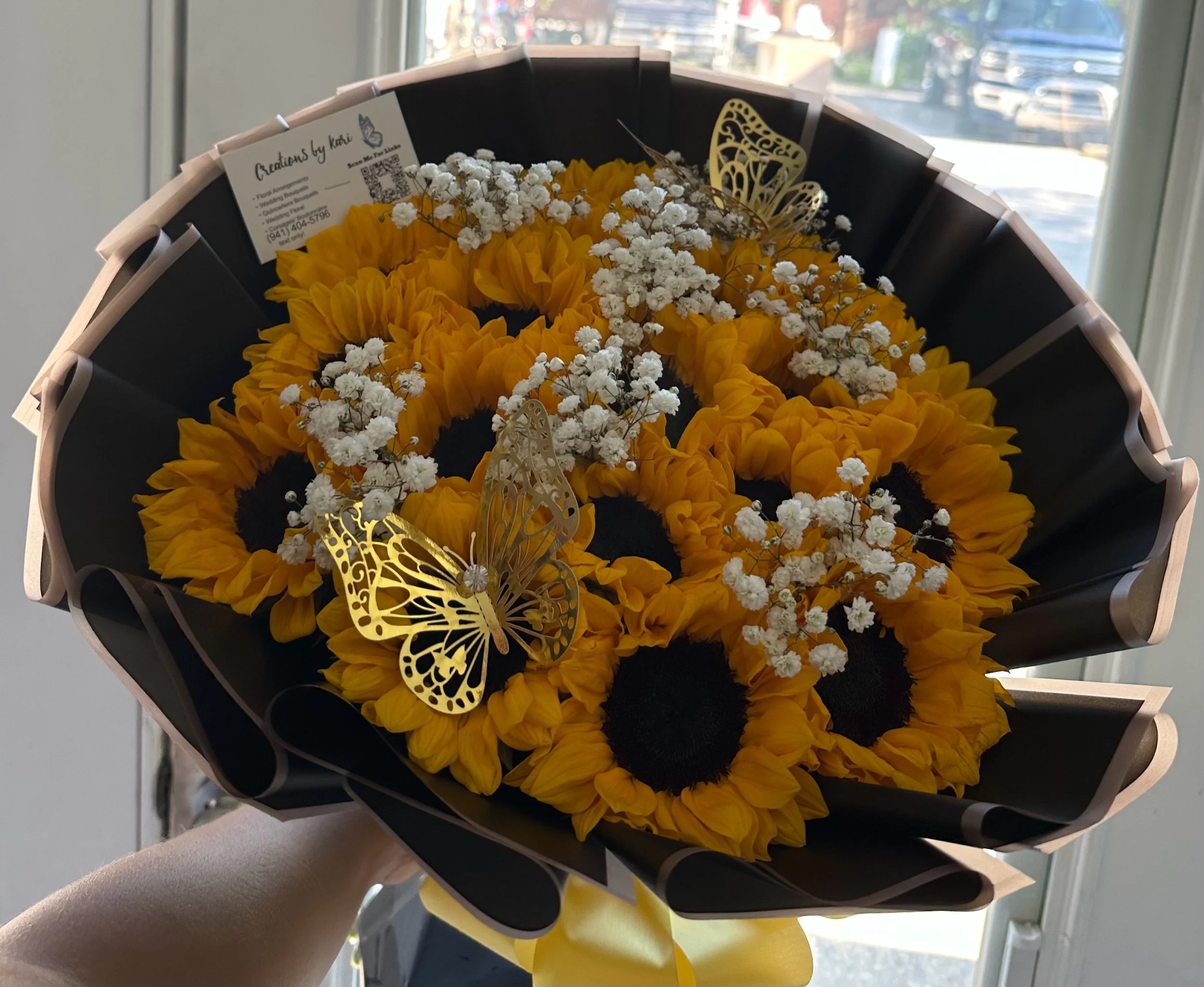 Sunflower bouquet accented with clusters of white baby’s breath and decorative gold butterflies.