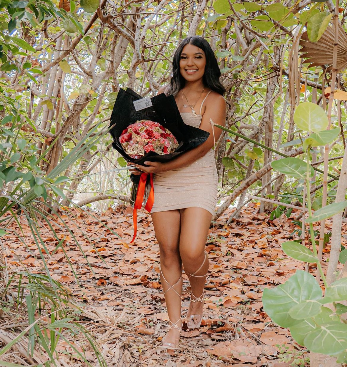 Red and pink floral bouquet wrapped in black with red ribbon