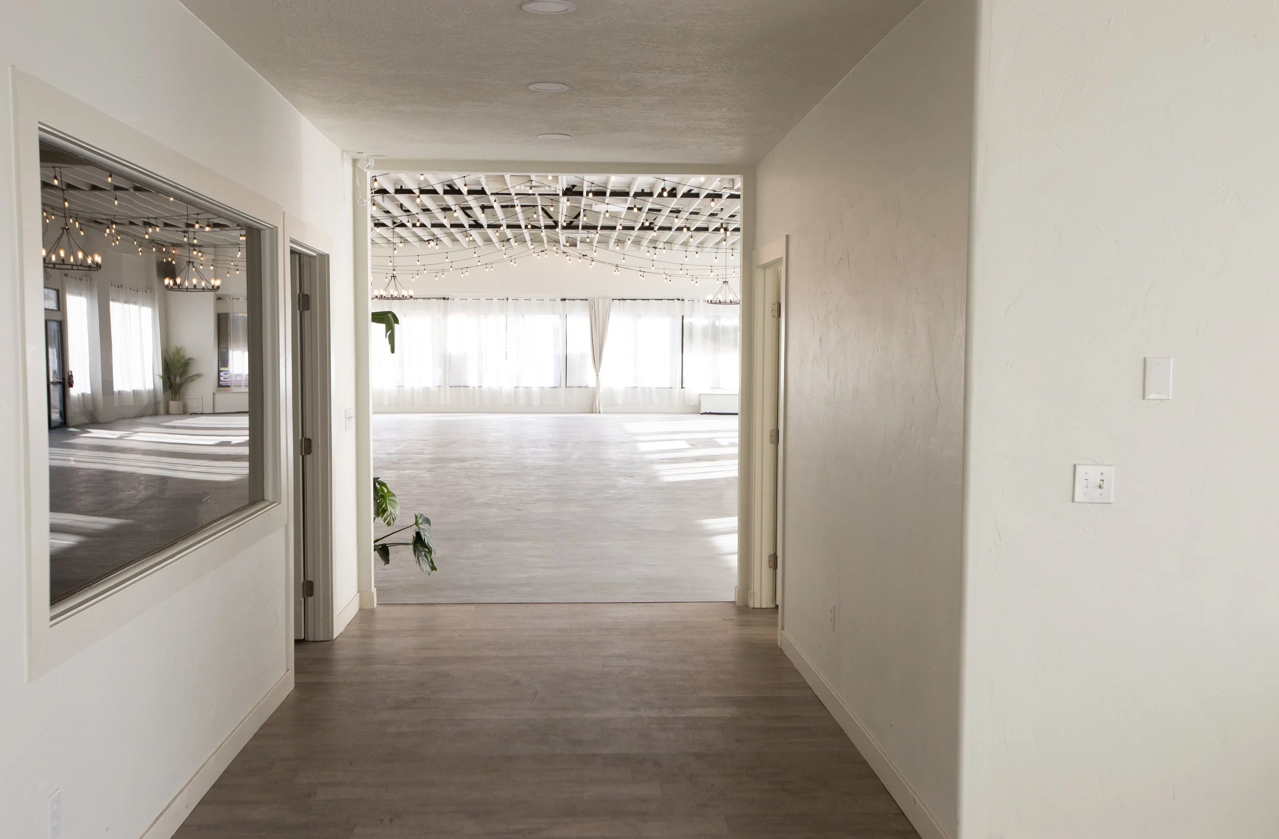 Inviting hallway entrance with natural light

A transitional space leading into the main venue, framed by white walls and glass doors, with light pouring in from the far end.